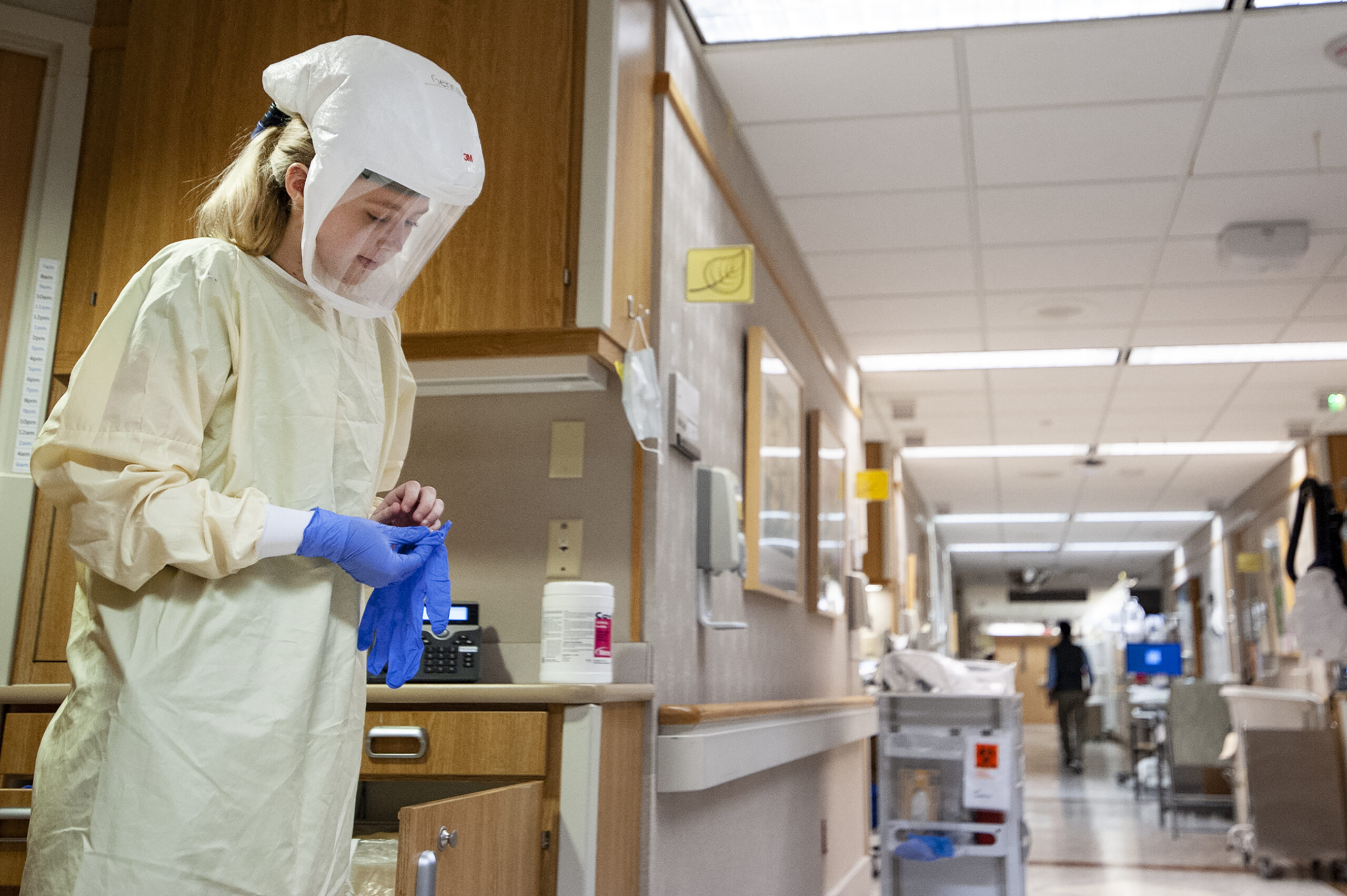 A nurse puts on gloves before caring for a Covid patient