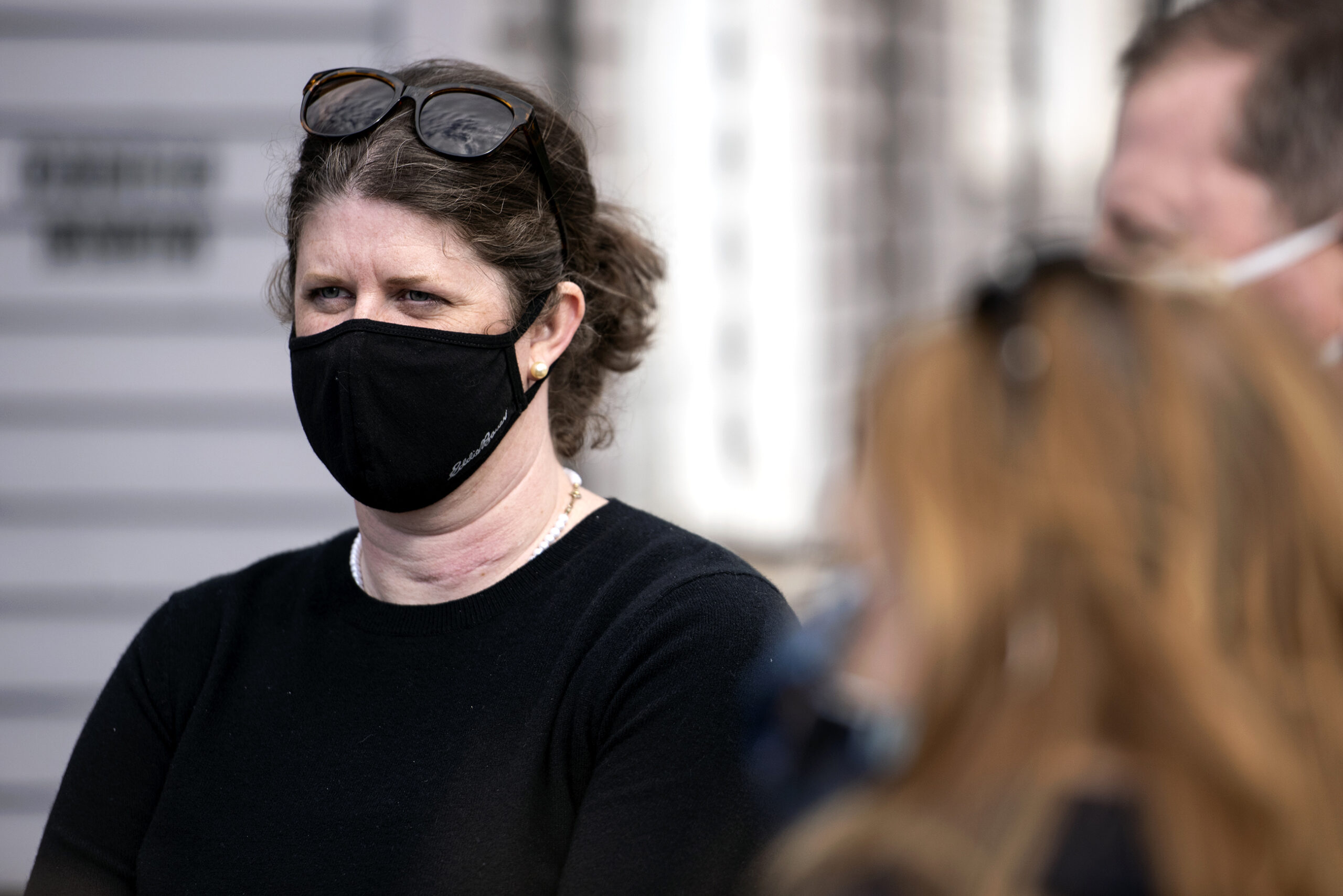 A woman in a face mask attends a campaign event outside.