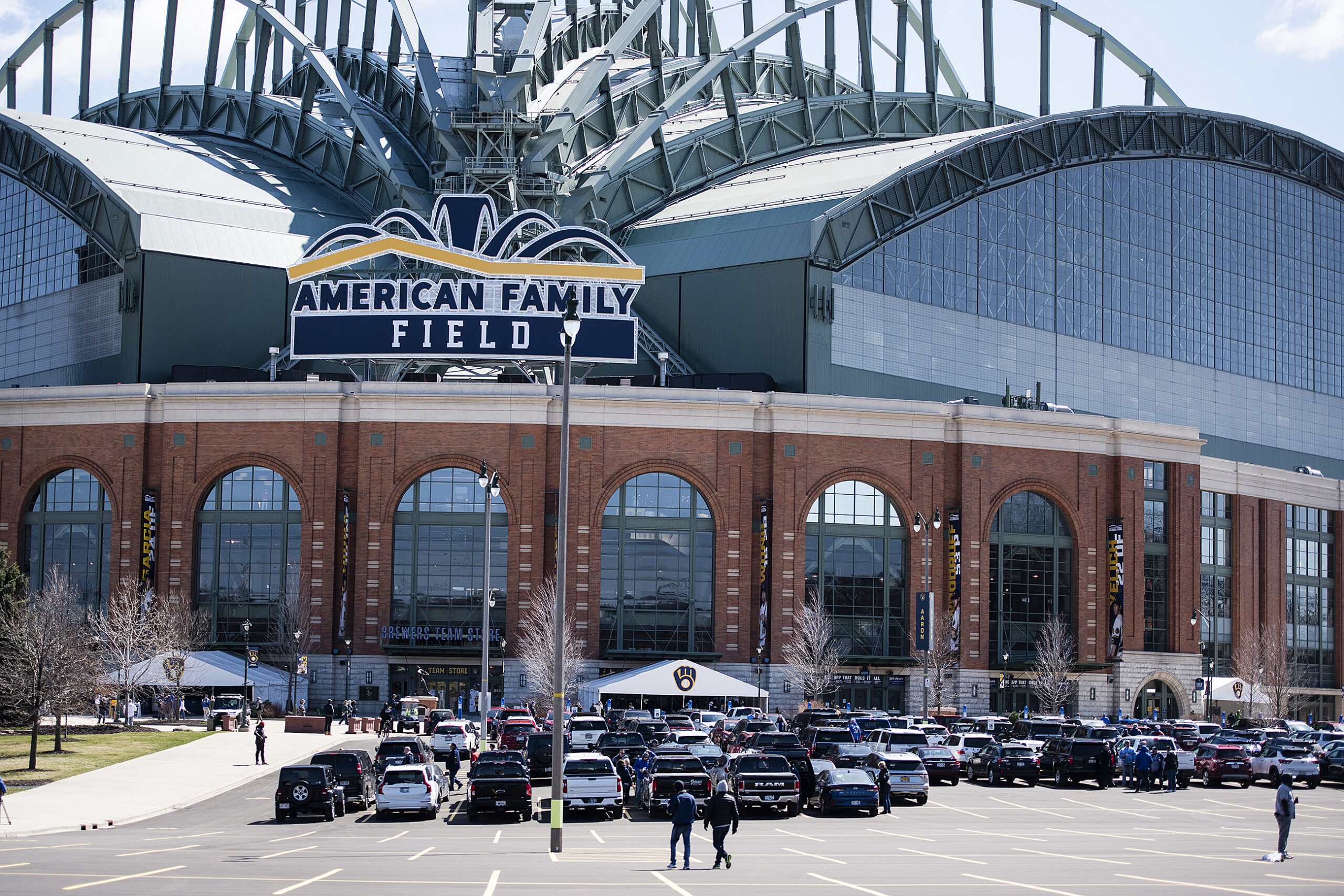 Cars are parked in front of American Family Field on a sunny day.