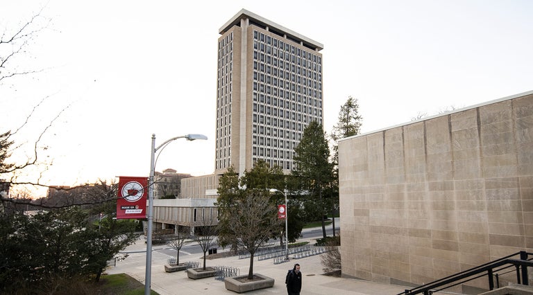 A pedestrian walks on a sidewalk near Van Hise Hall