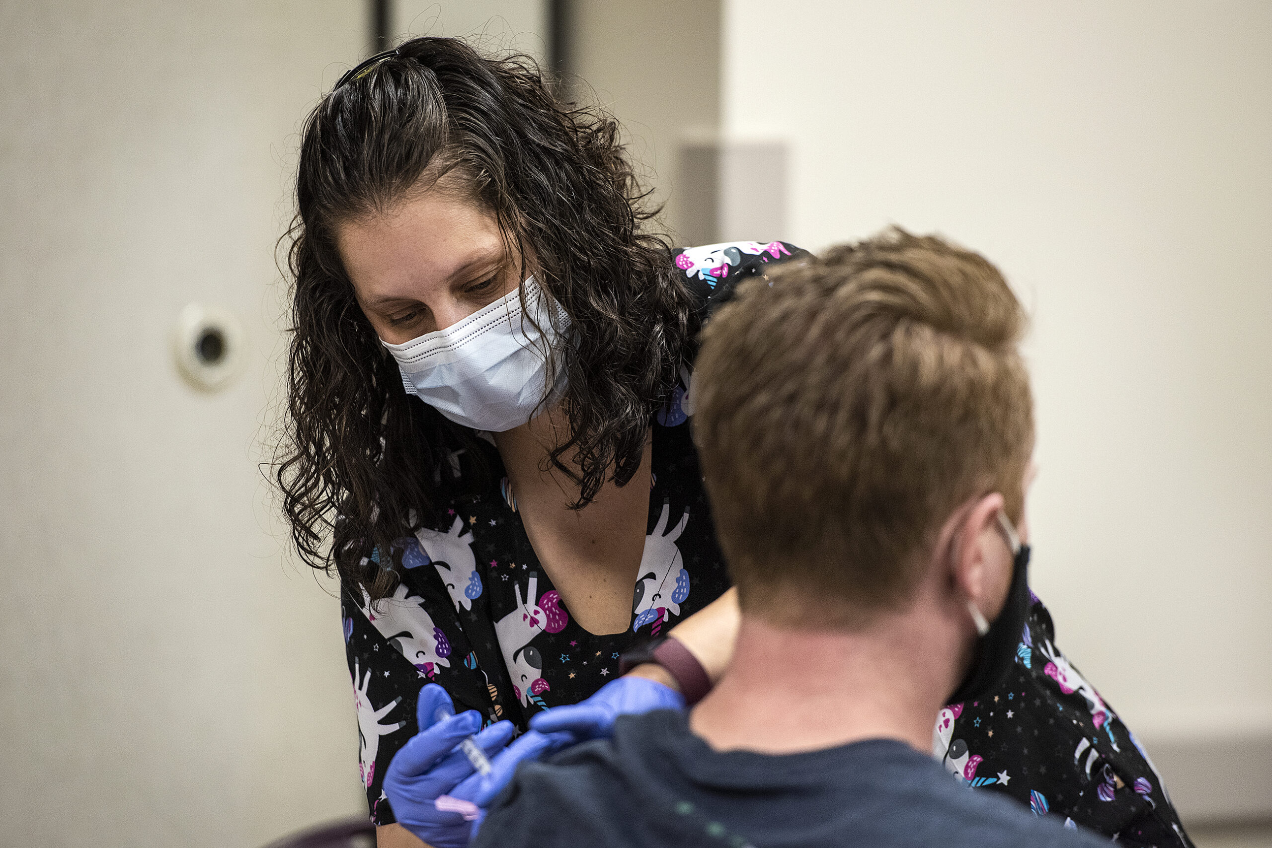 a nurse in a face mask holds a syringe after giving a vaccine