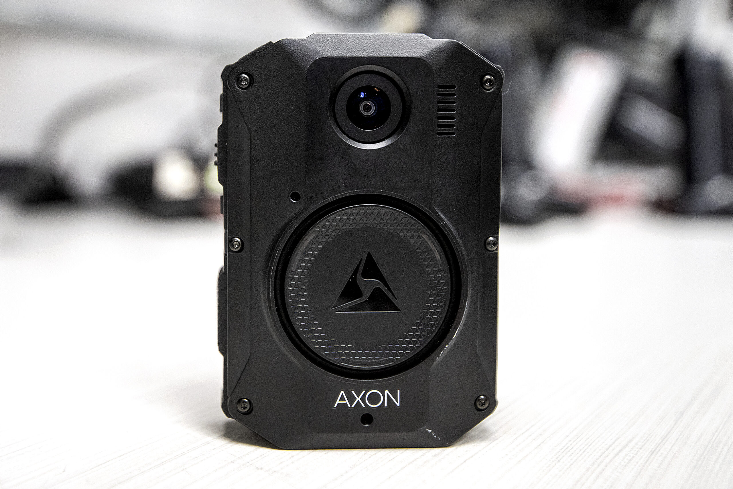 A rectangular black device has a camera lens facing outward.