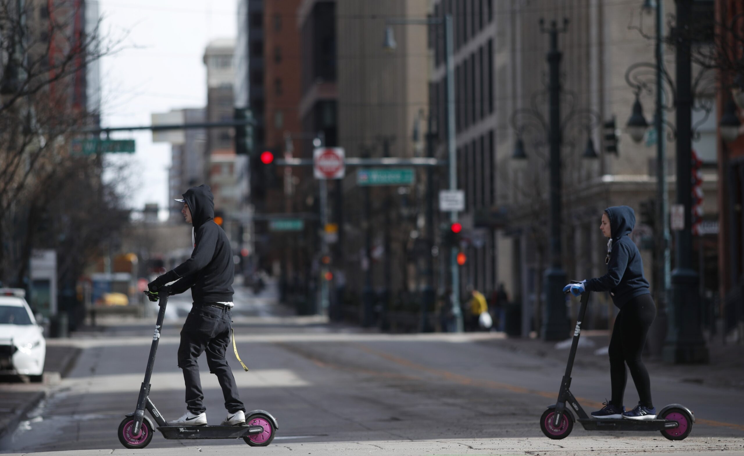 Riders cross a deserted road on electric scooters