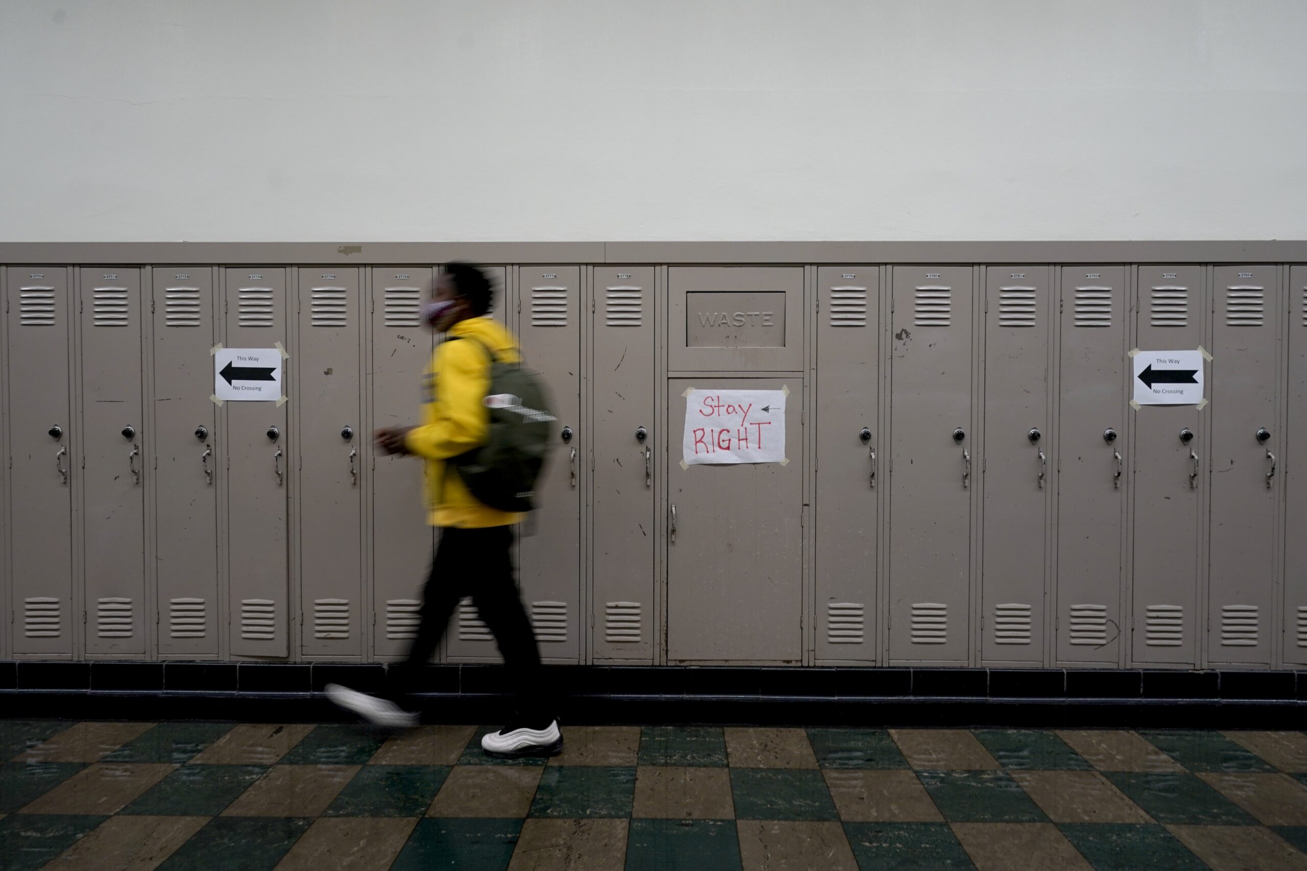 A student walks on the right side of a hallway to avoid contact with other students
