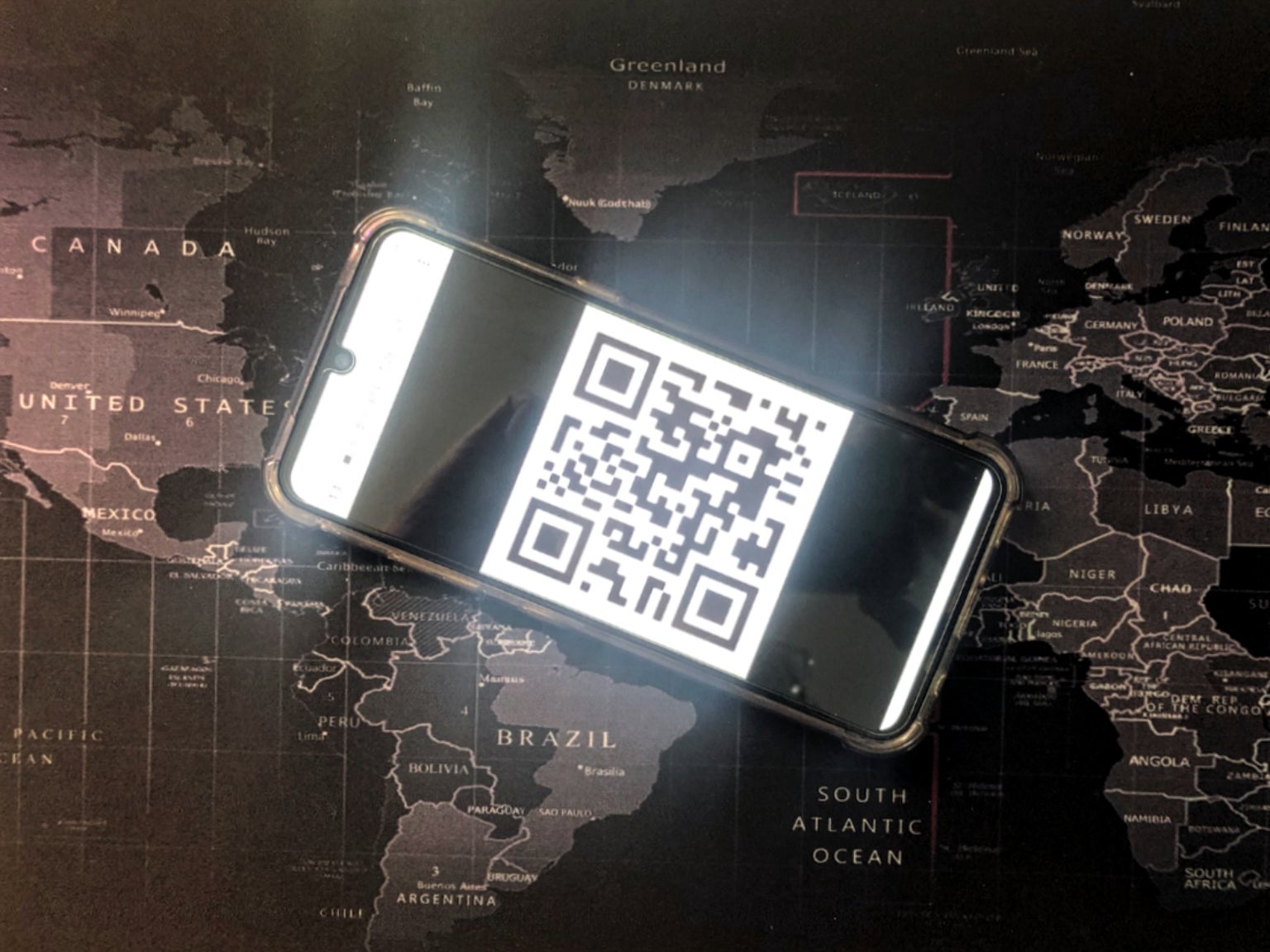 A phone shows a QR code for a vaccine passport