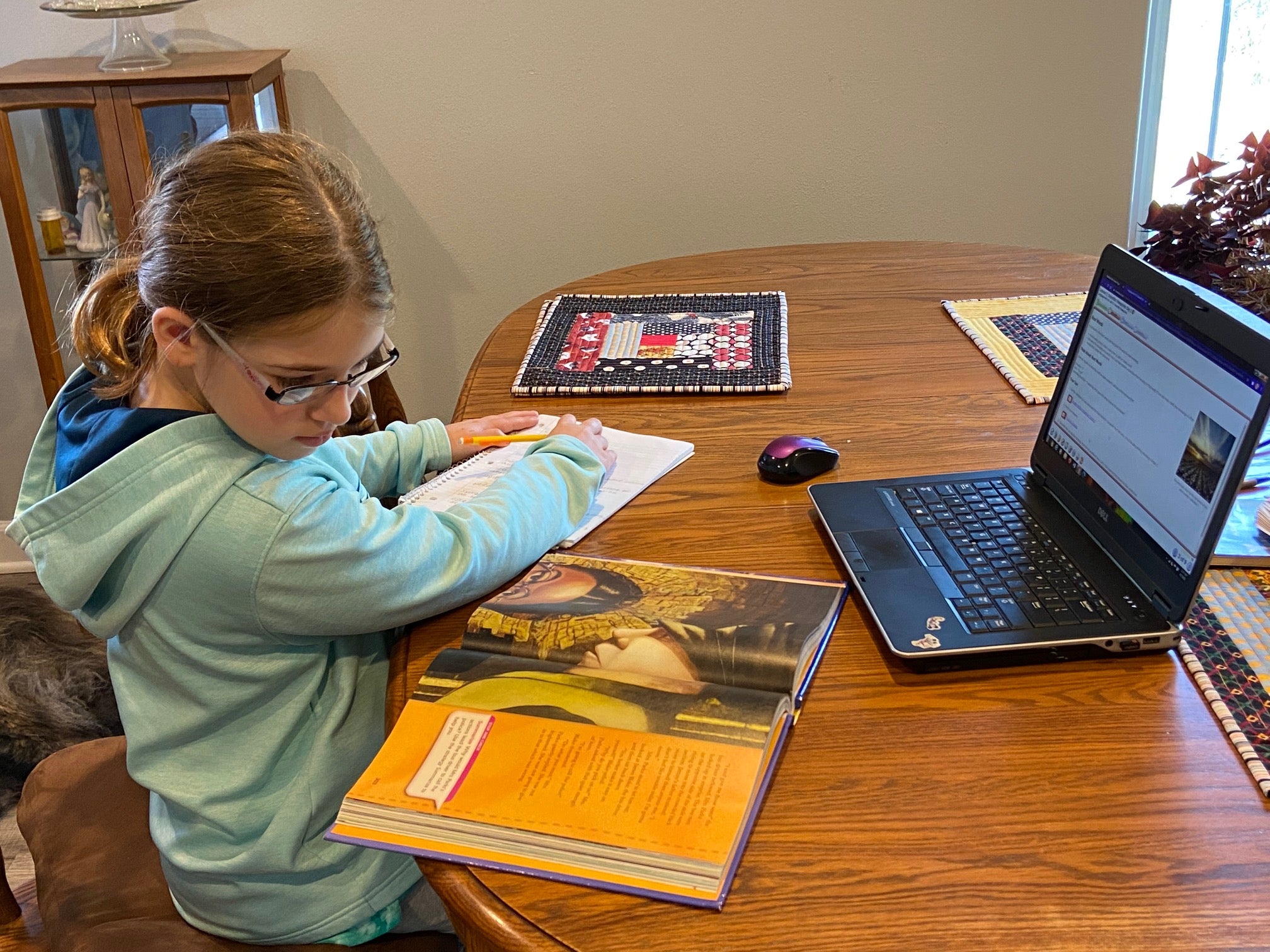 A girl works on a school assignment while looking at a computer