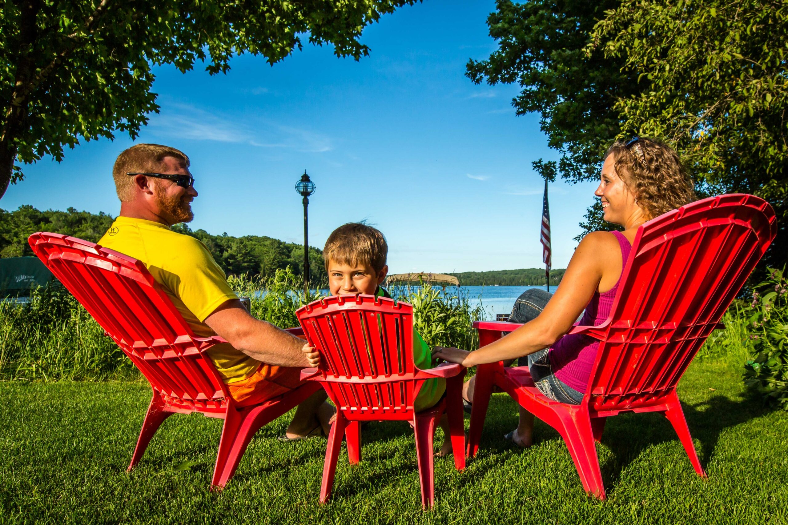 A family sitting in red chairs on a green lawn