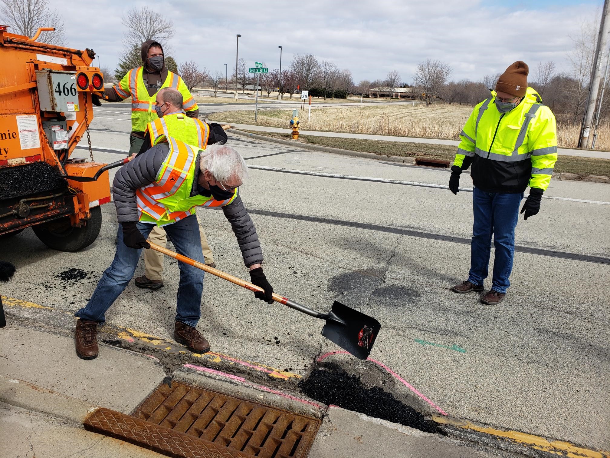 Wisconsin Gov. Tony Evers (foreground) fills potholes during a recent series of events in northern Wisconsin designed to highlight his 2021-23 budget proposal