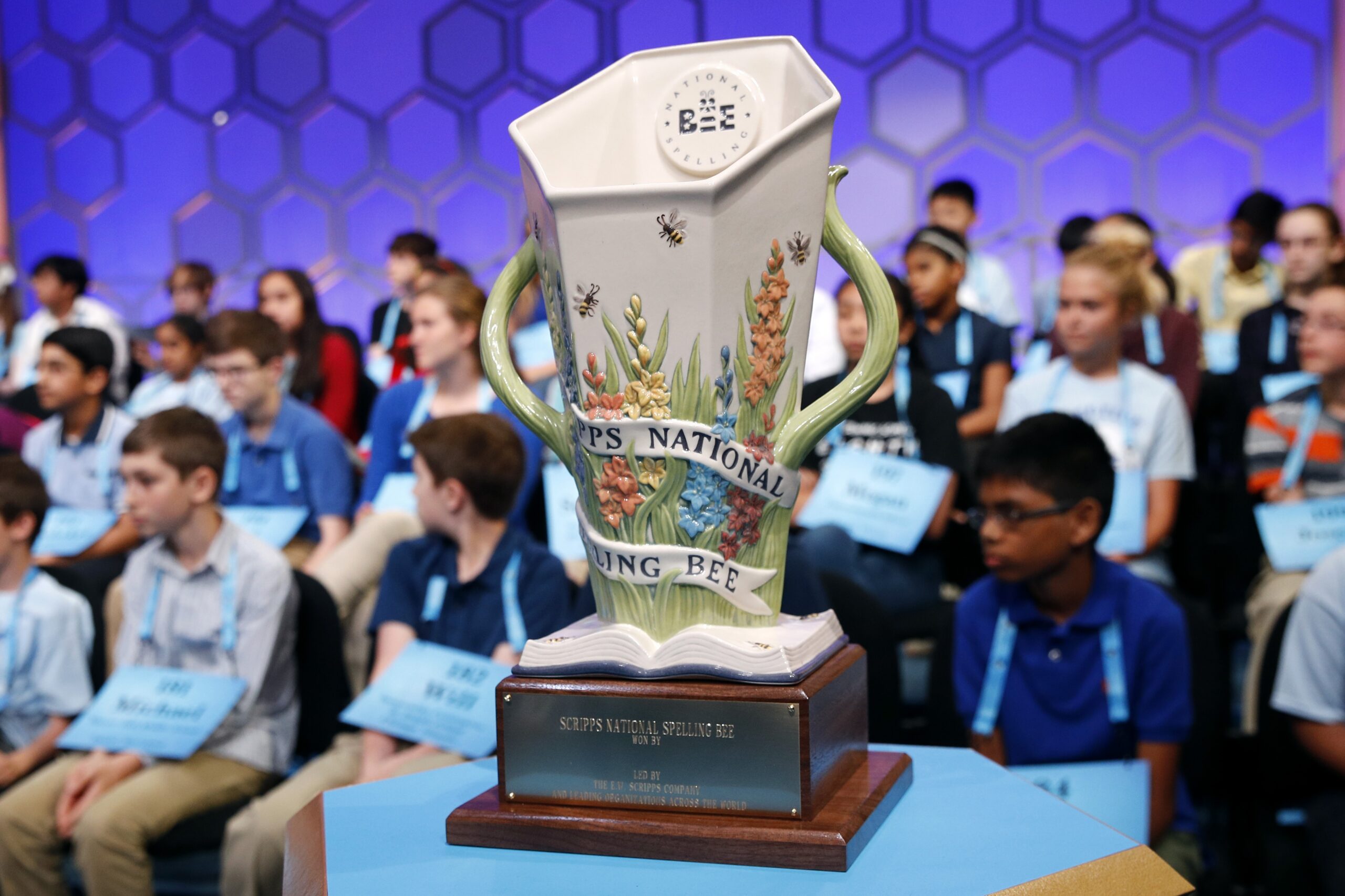 The Scripps National Spelling Bee trophy sits in front of competitors