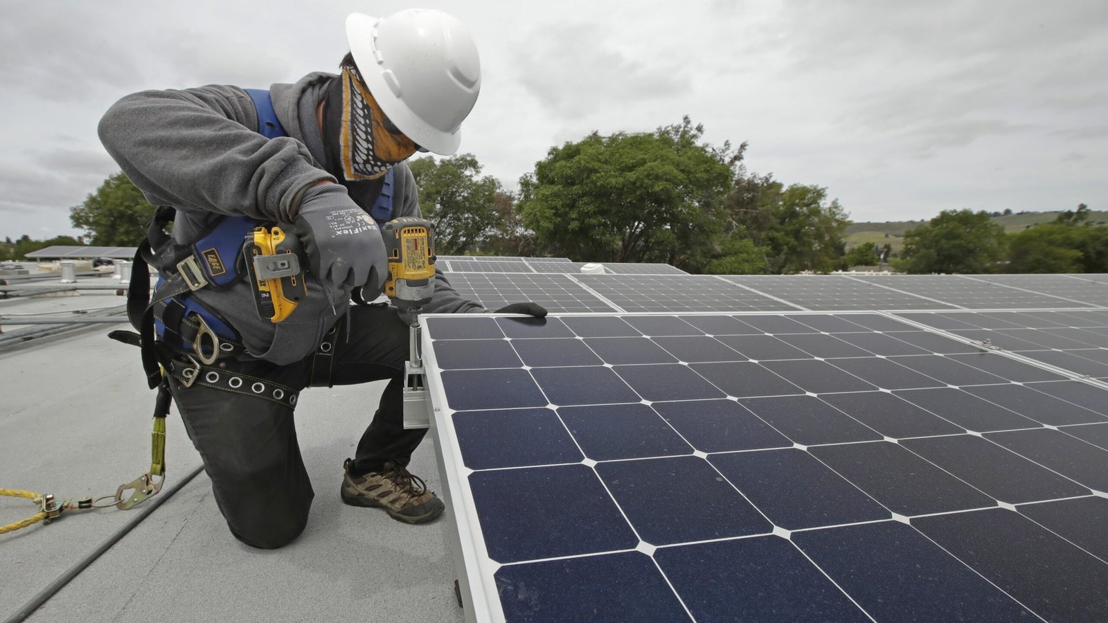 A solar installer works on a panel