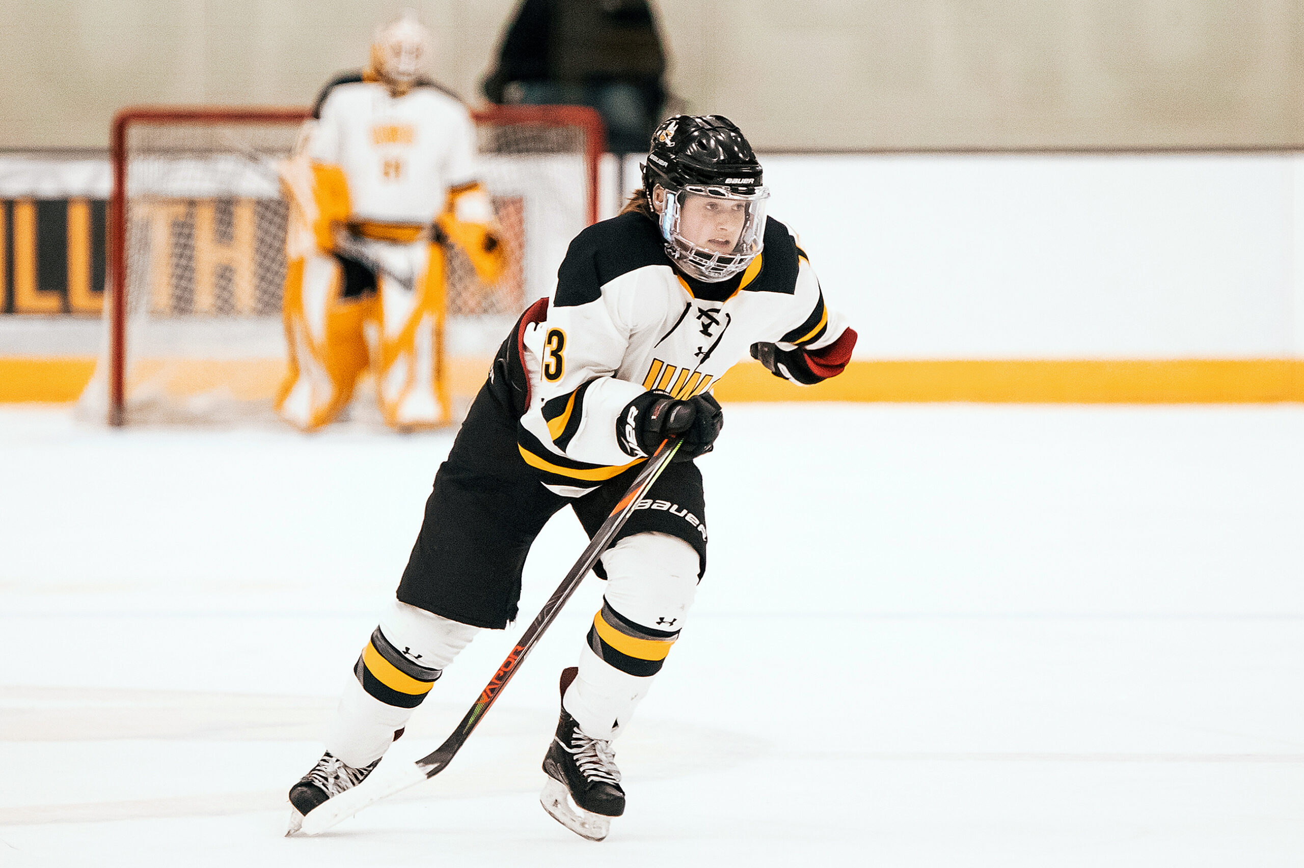 A hockey player looks forward as she moves across the ice.