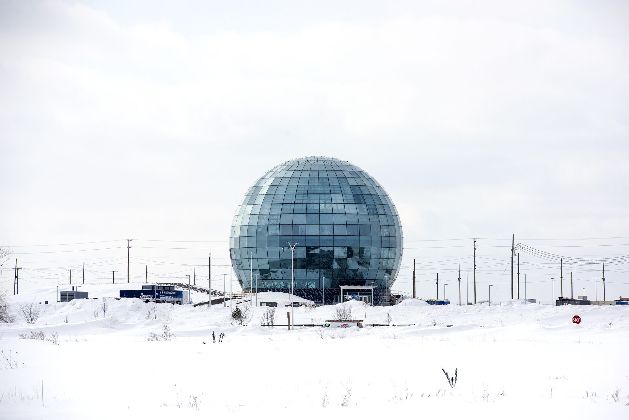 A large glass globe is surrounded by snow and a white cloudy sky.
