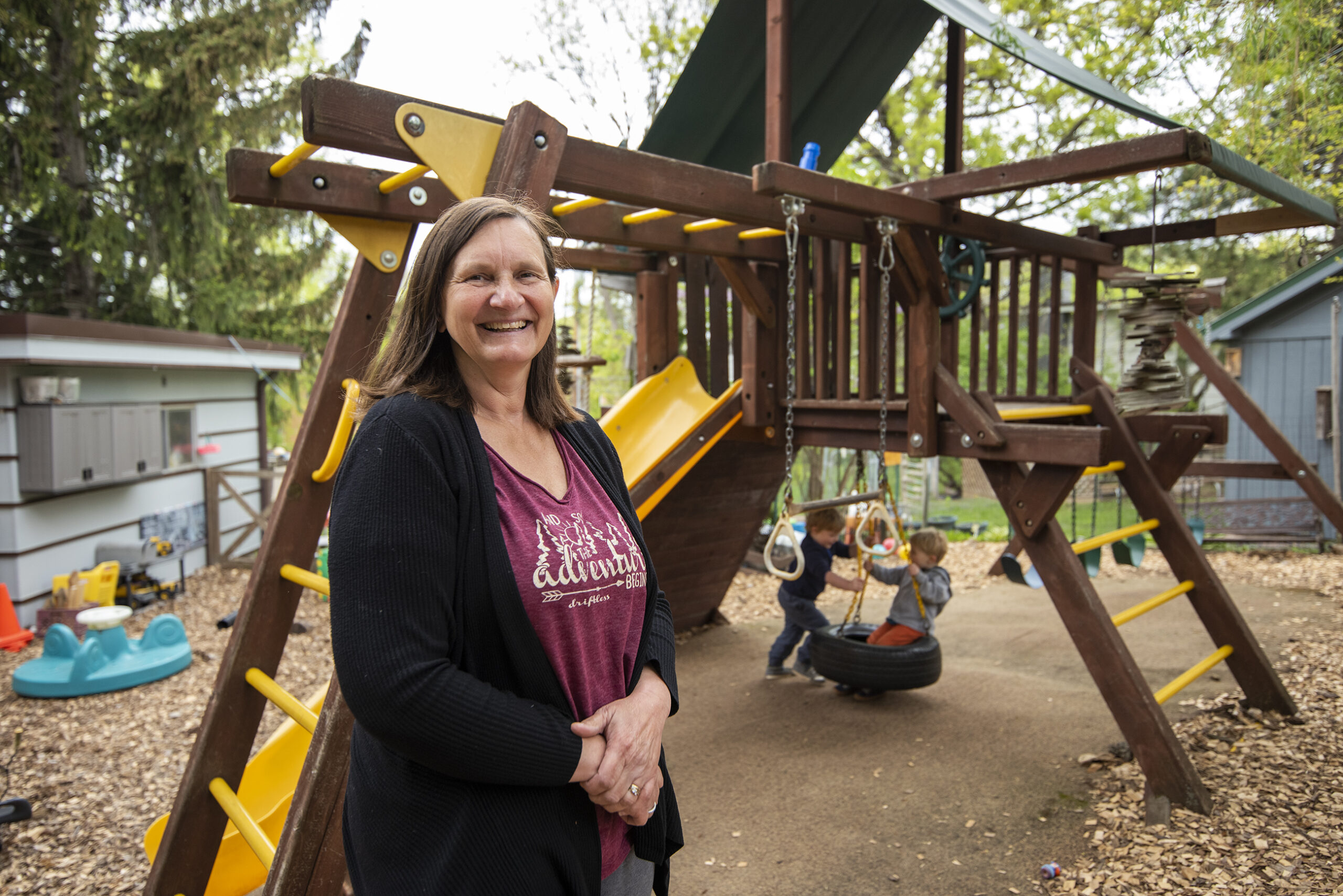 Sike O'Donnell stands in front of the playground as two children swing on a tire swing behind her.