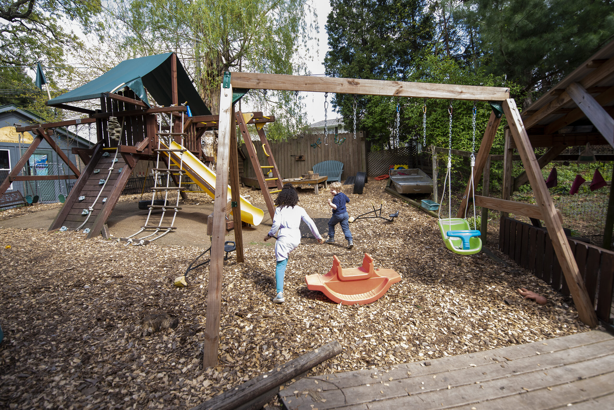 Two children are seen from behind as they run up to playground equipment.