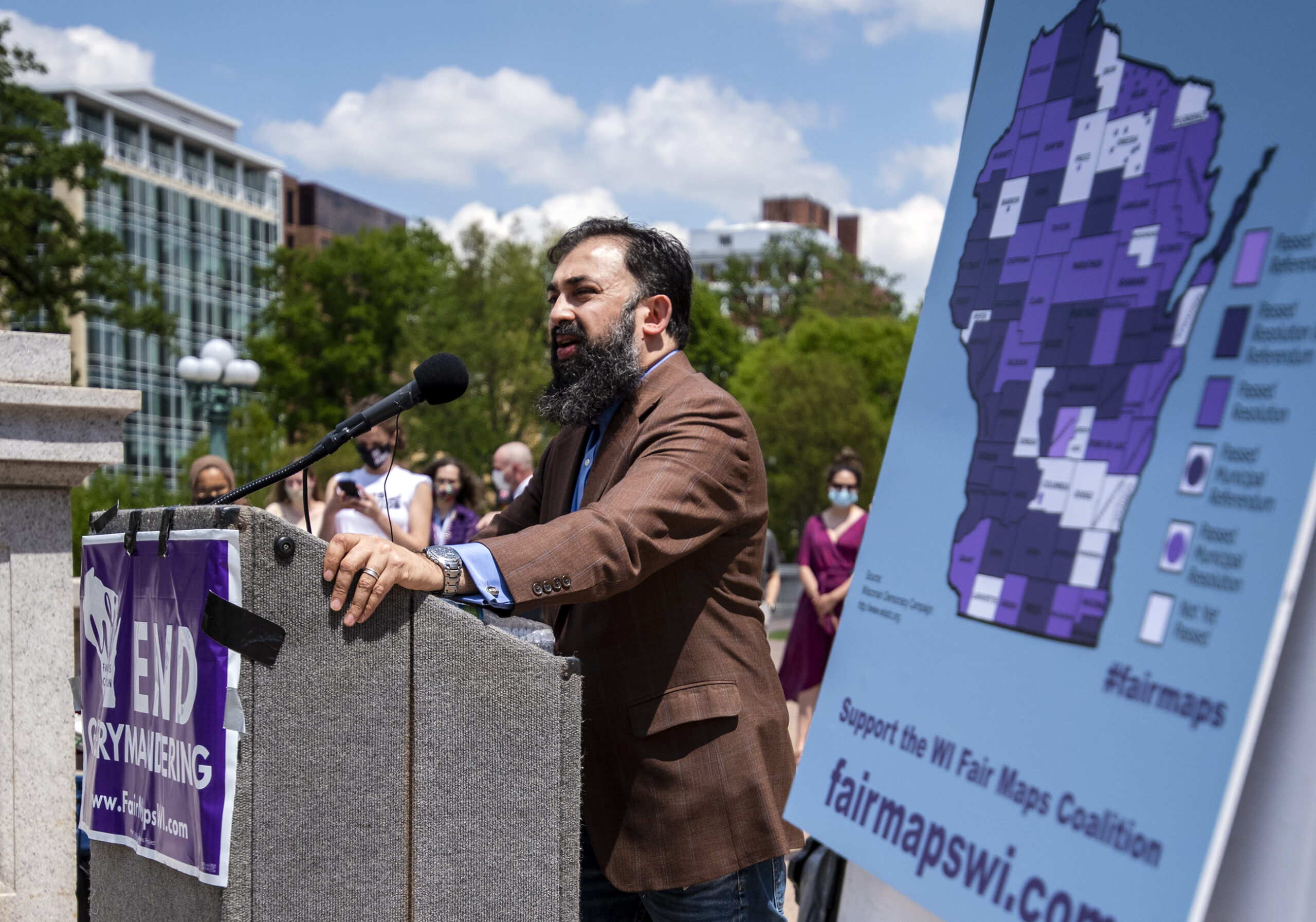 A man speaks at a podium next to a map of Wisconsin.