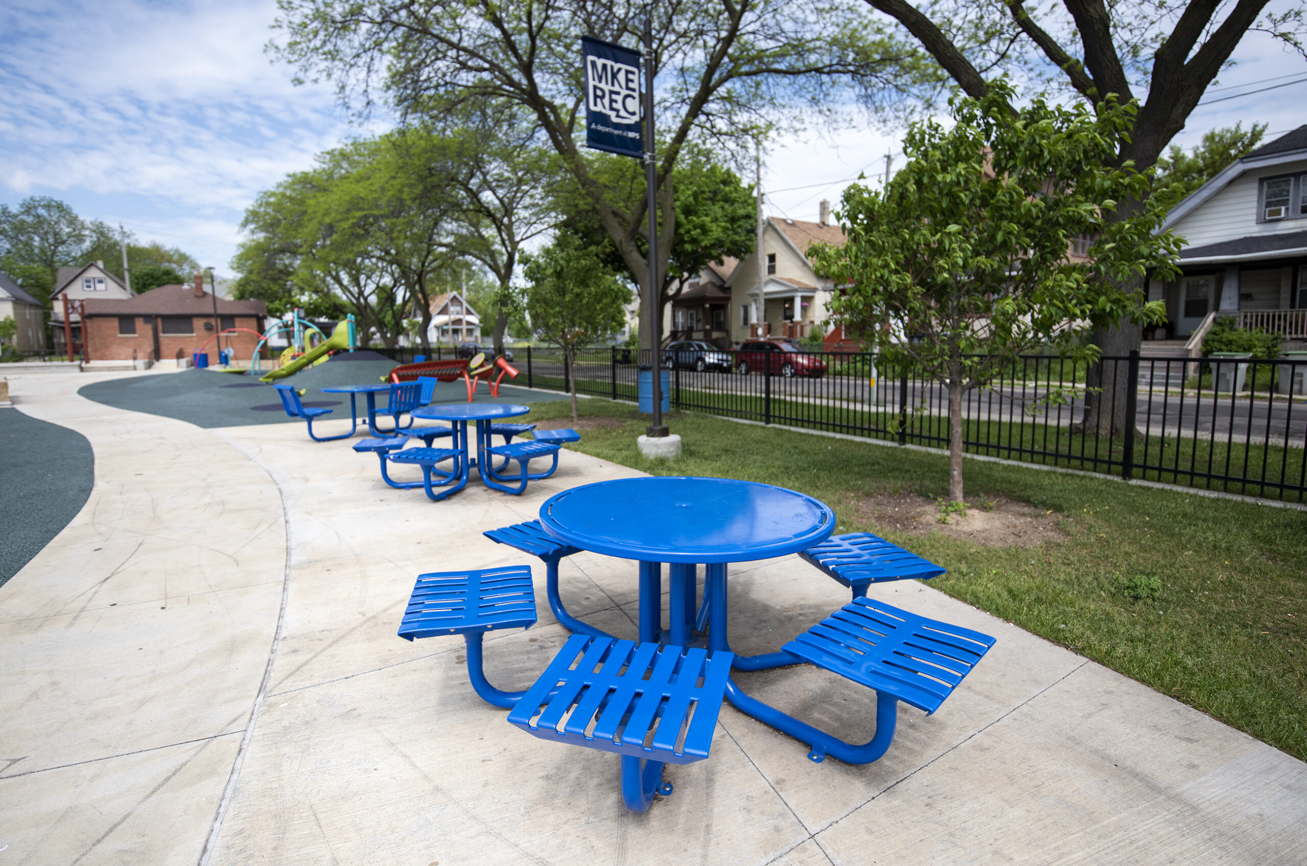 A blue picnic table at a park on a sunny day.