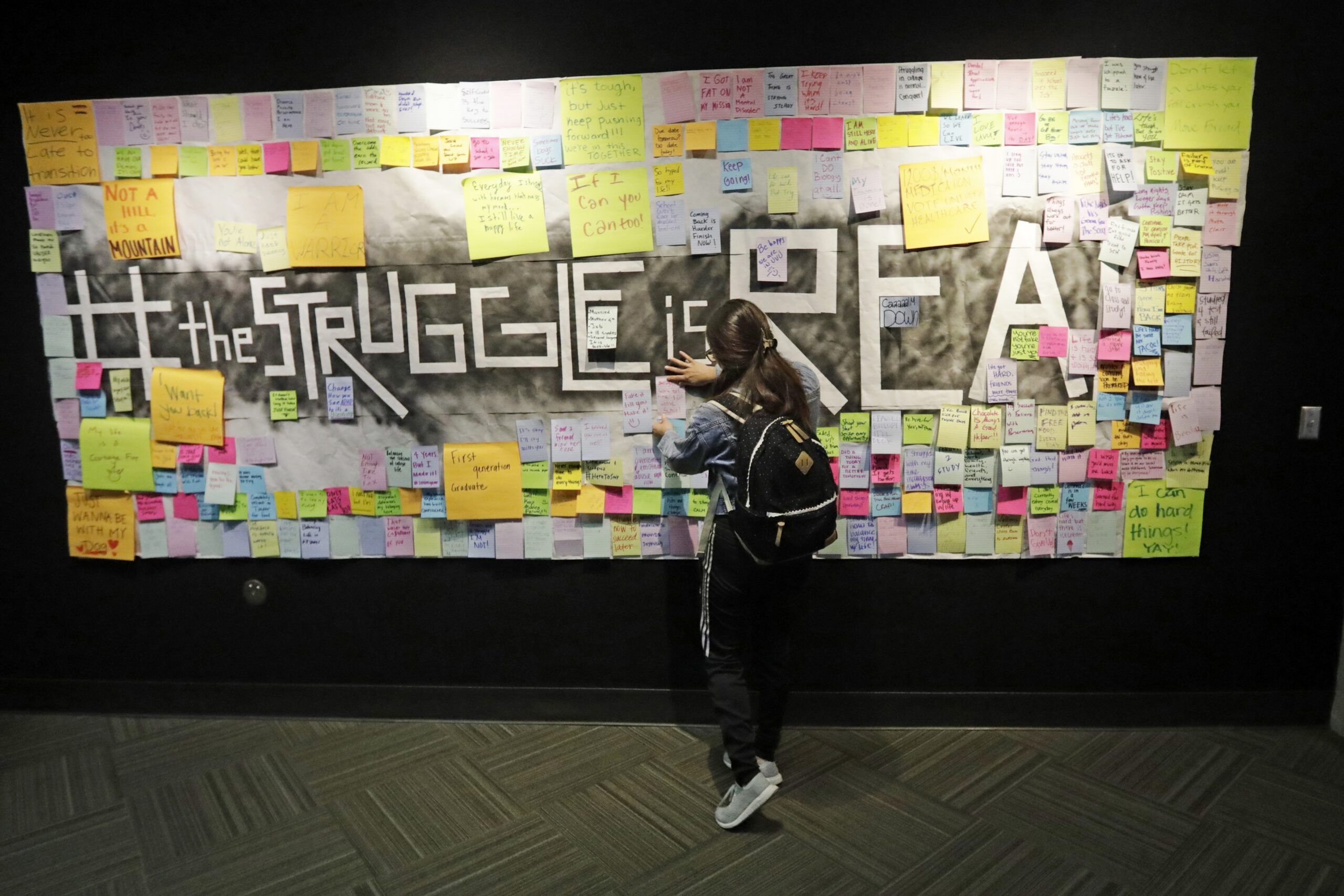 a student attaches a note to the Resilience Project board