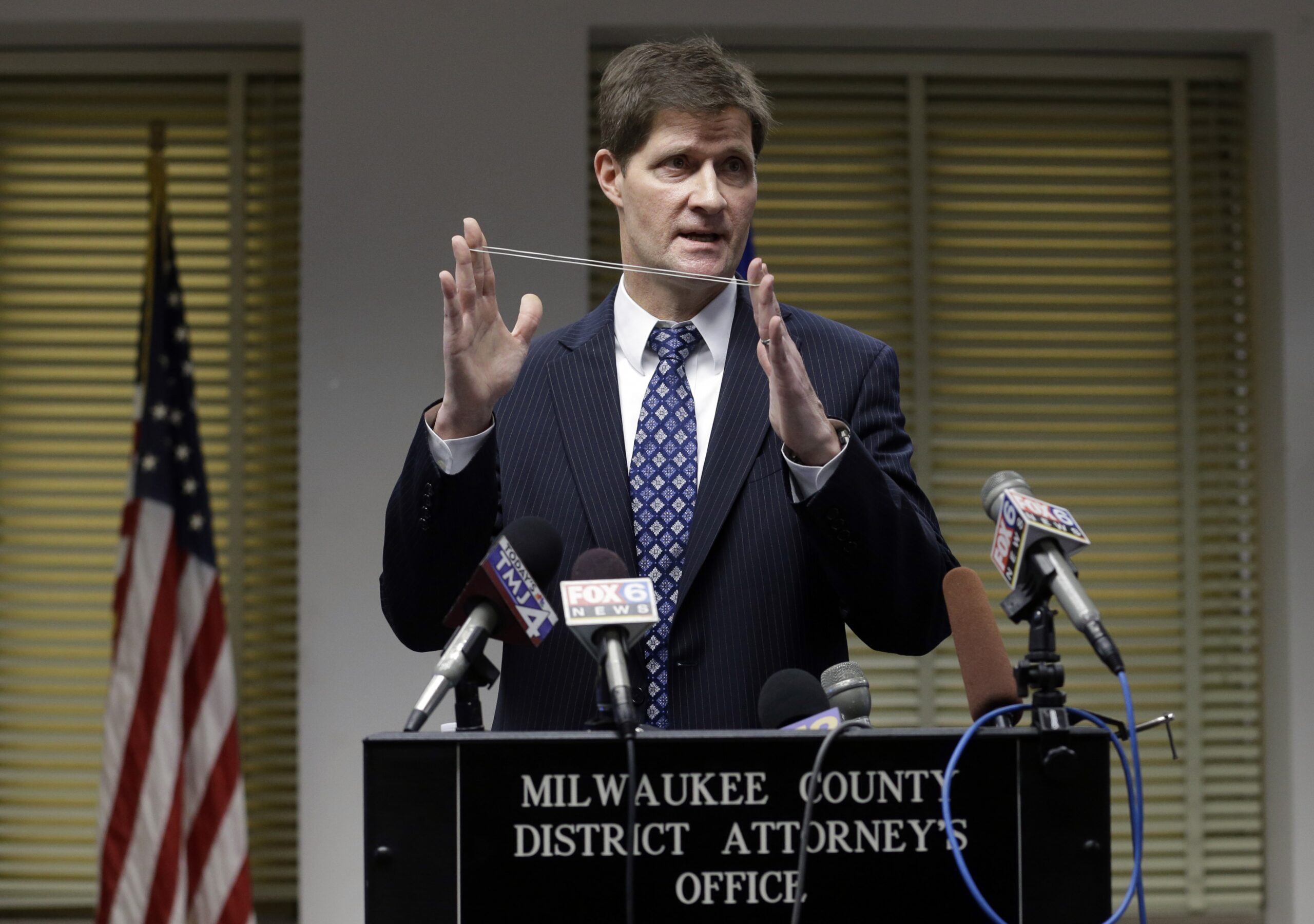 Milwaukee County District Attorney John Chisholm demonstrates bullet trajectory.