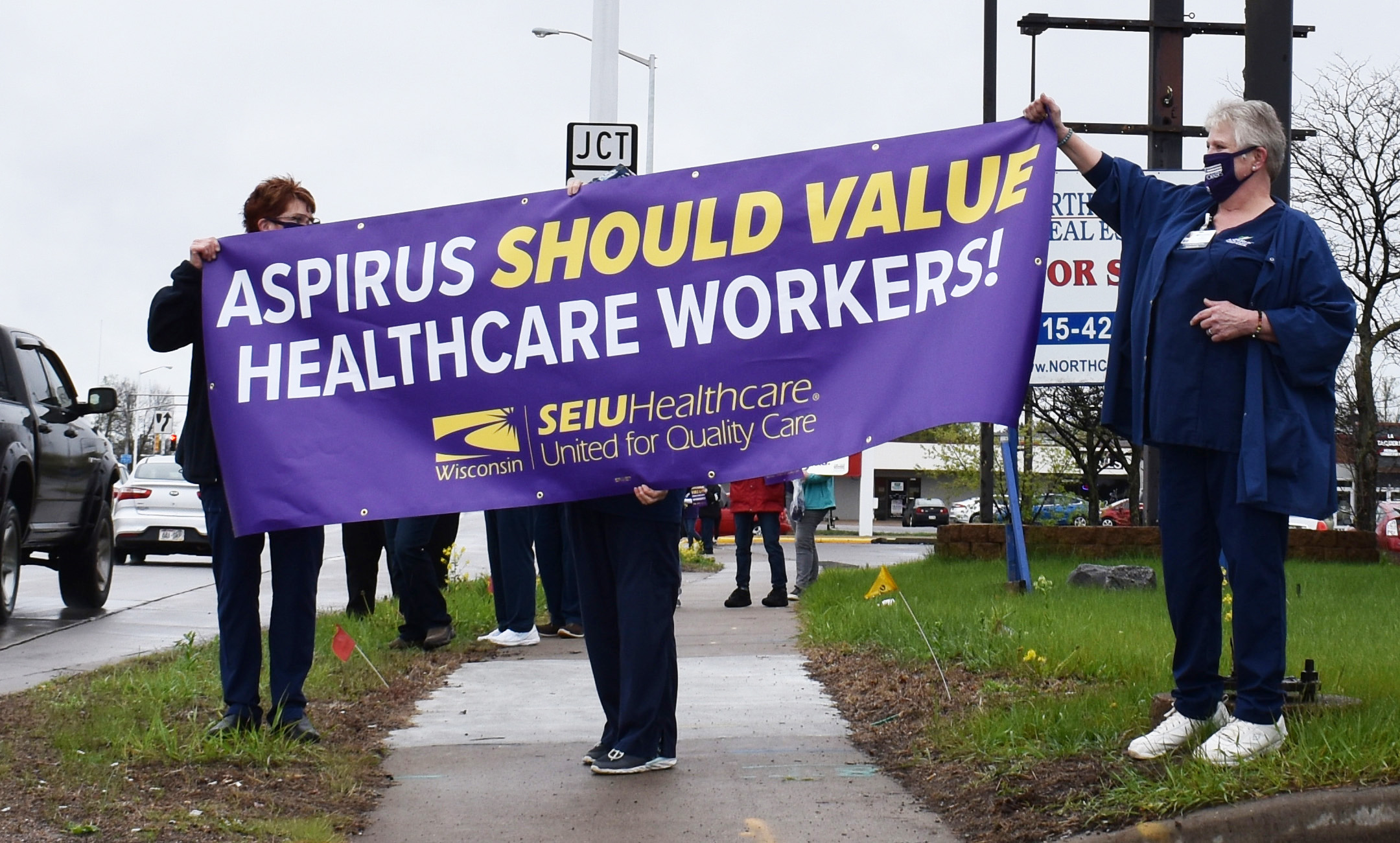 Sarah Von Loh and Eve Mork hold a sign reading "Aspirus should value healthcare workers!" at a rally in Wisconsin Rapids