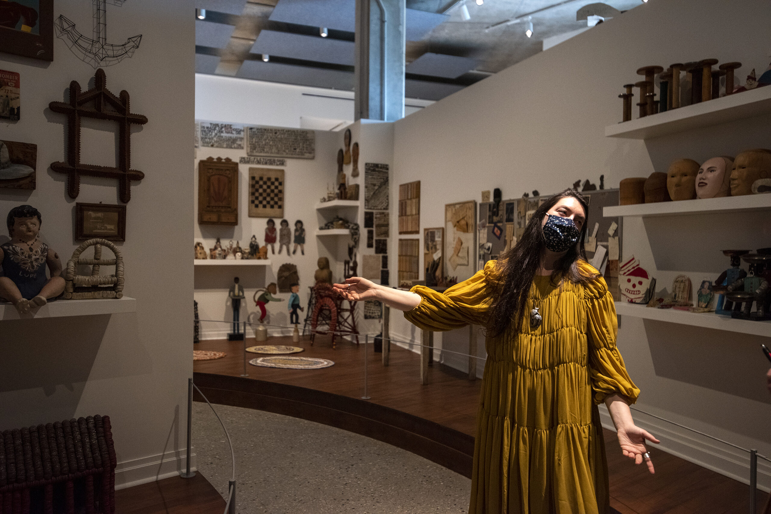 A woman gestures as she walks through an art display.