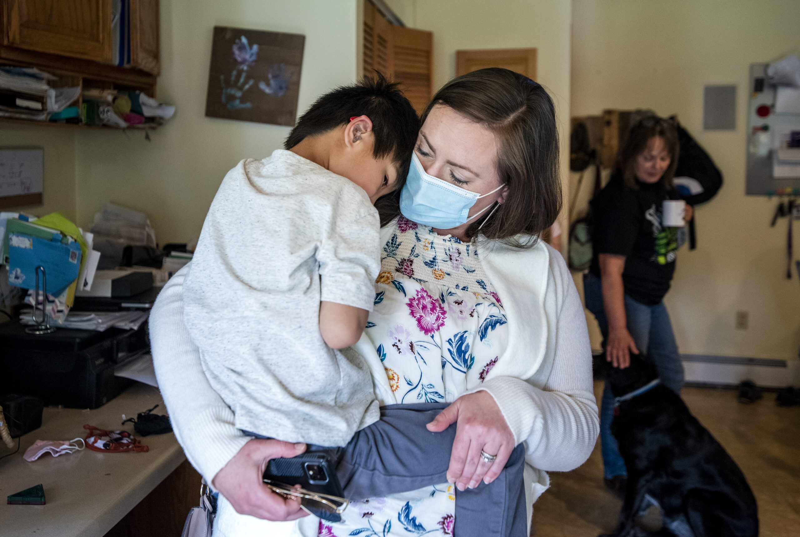 A woman holds a child who is leaning on her shoulder.