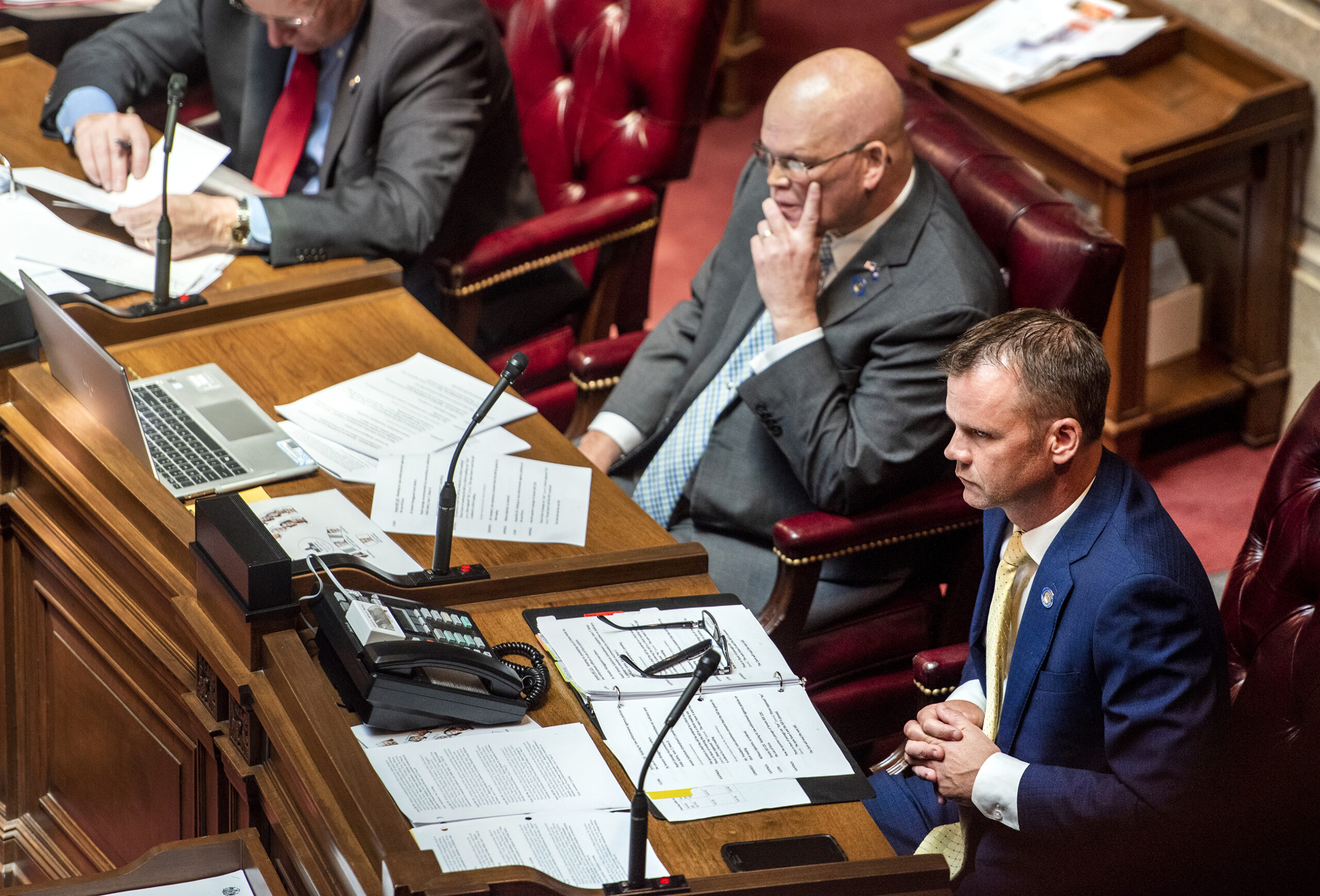 Senators sit at their desks.