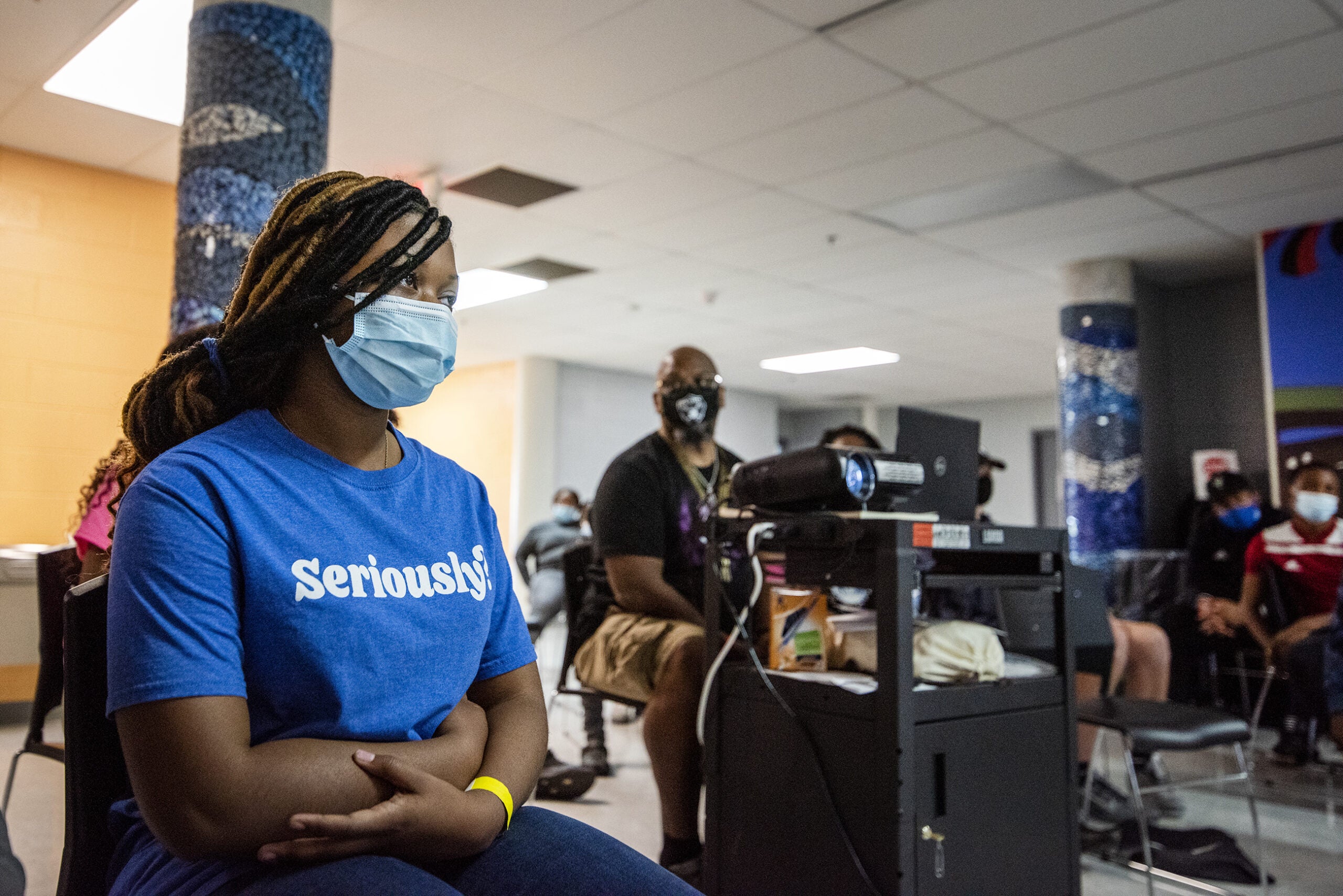 Students wear face masks as they watch a something projected in a classroom.