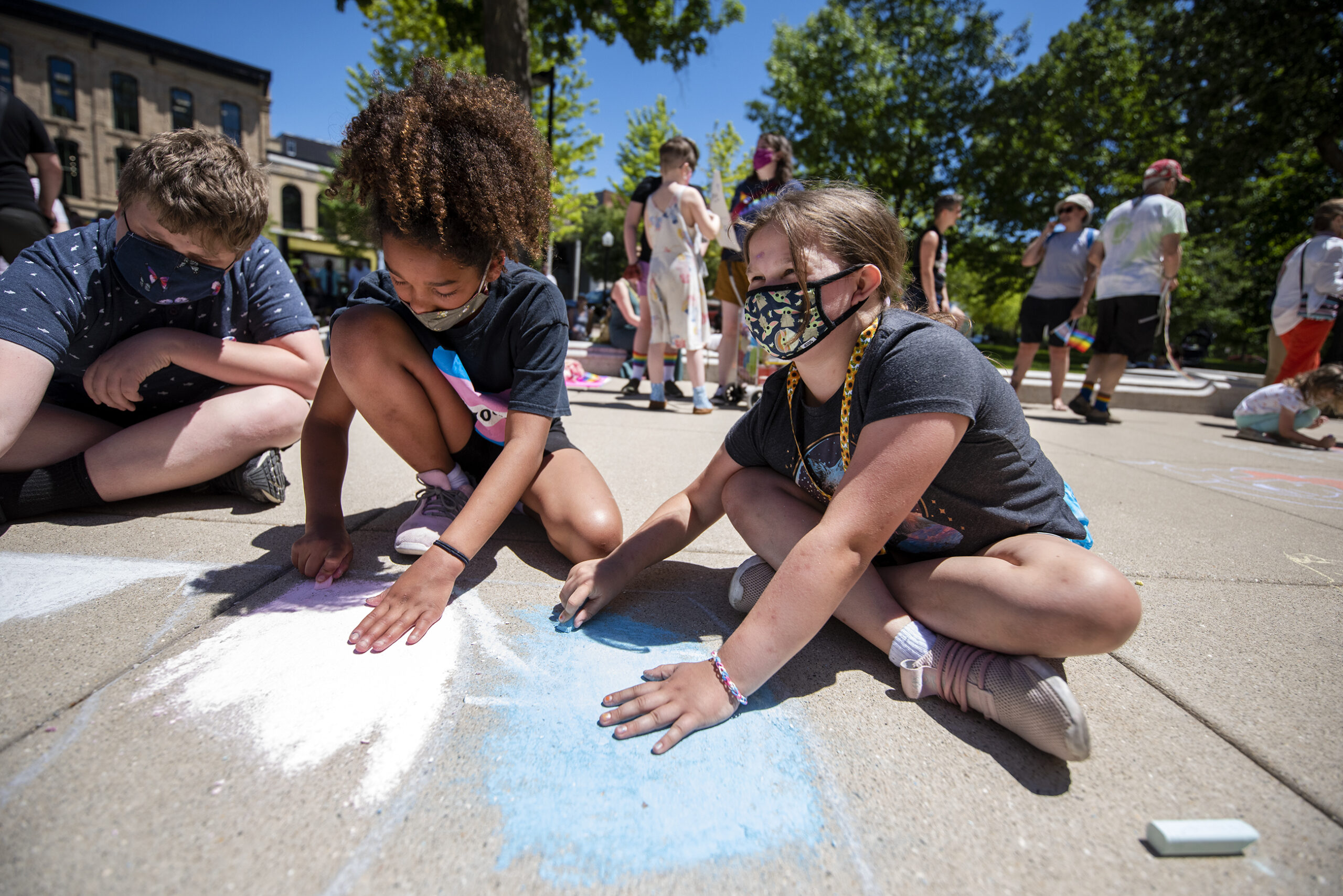 Two children color with chalk outside.