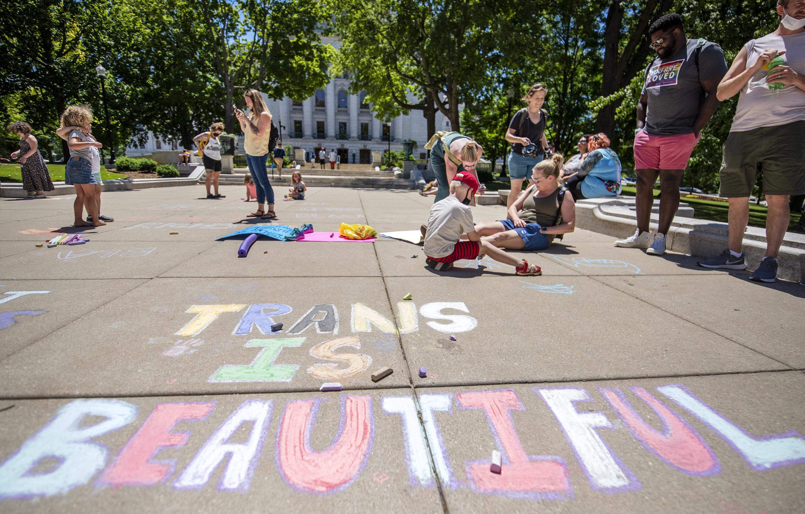 The words "Trans is beautiful" are written on a sidewalk.