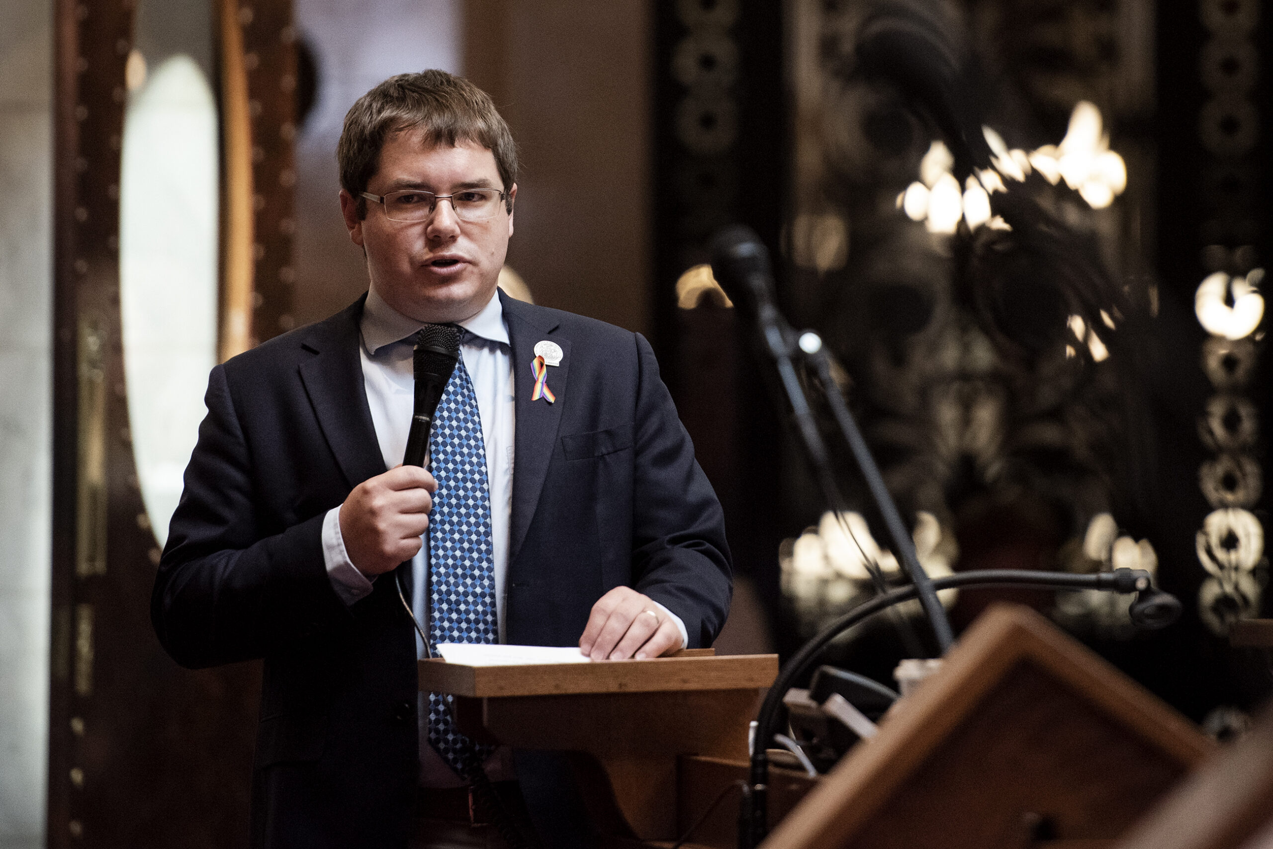 A man speaks at the front of the assembly floor.