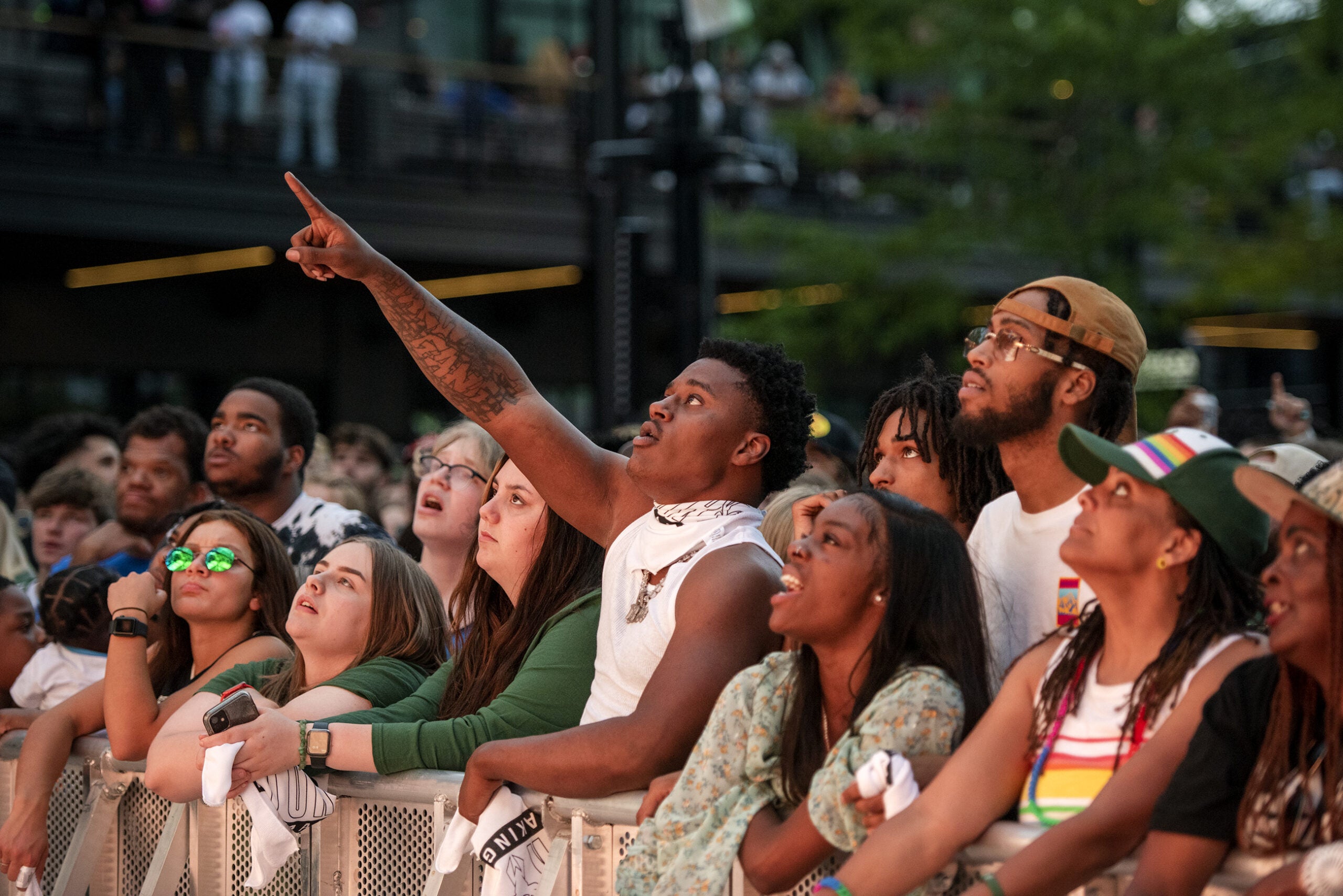 A fan points at the screen as he stands in a crowd of fans watching the game.