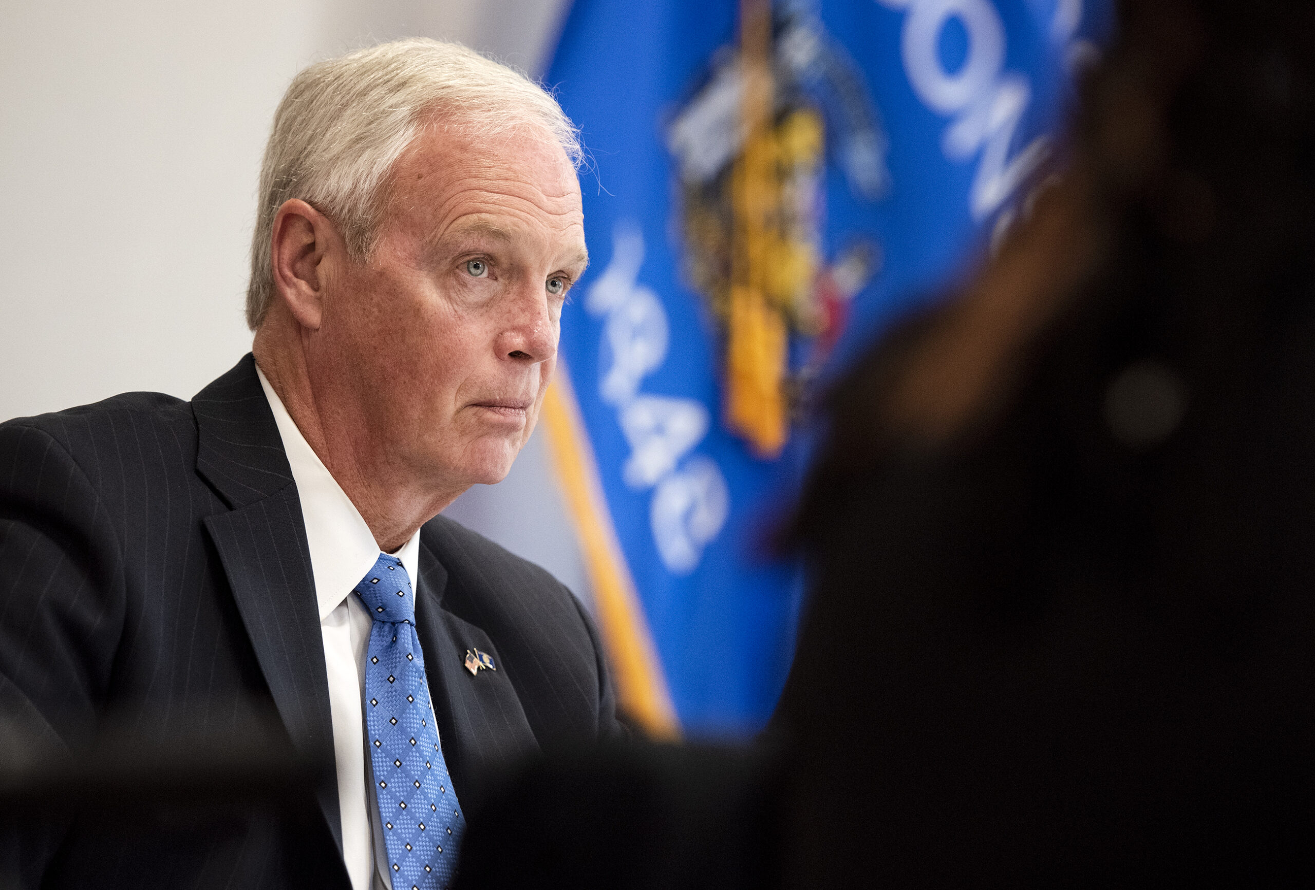 Sen. Ron Johnson is seen in front of a Wisconsin state flag at a press conference.