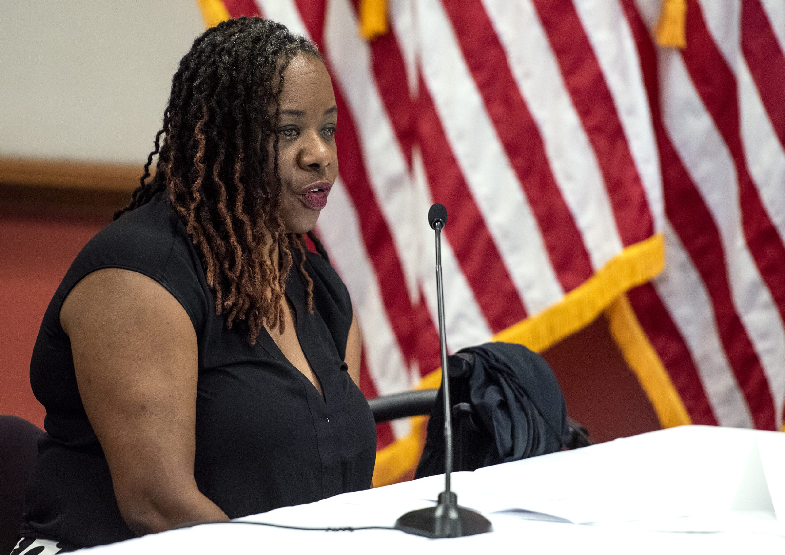 A woman sits at a table as she speaks at a press conference.