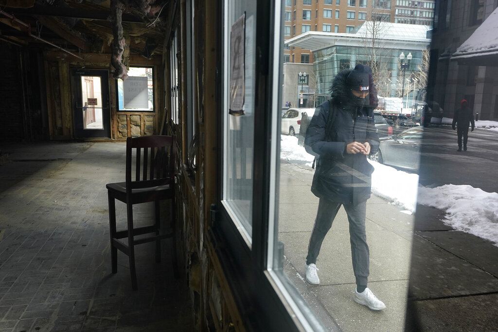 A passerby walks past an empty building that was formerly a restaurant in Boston