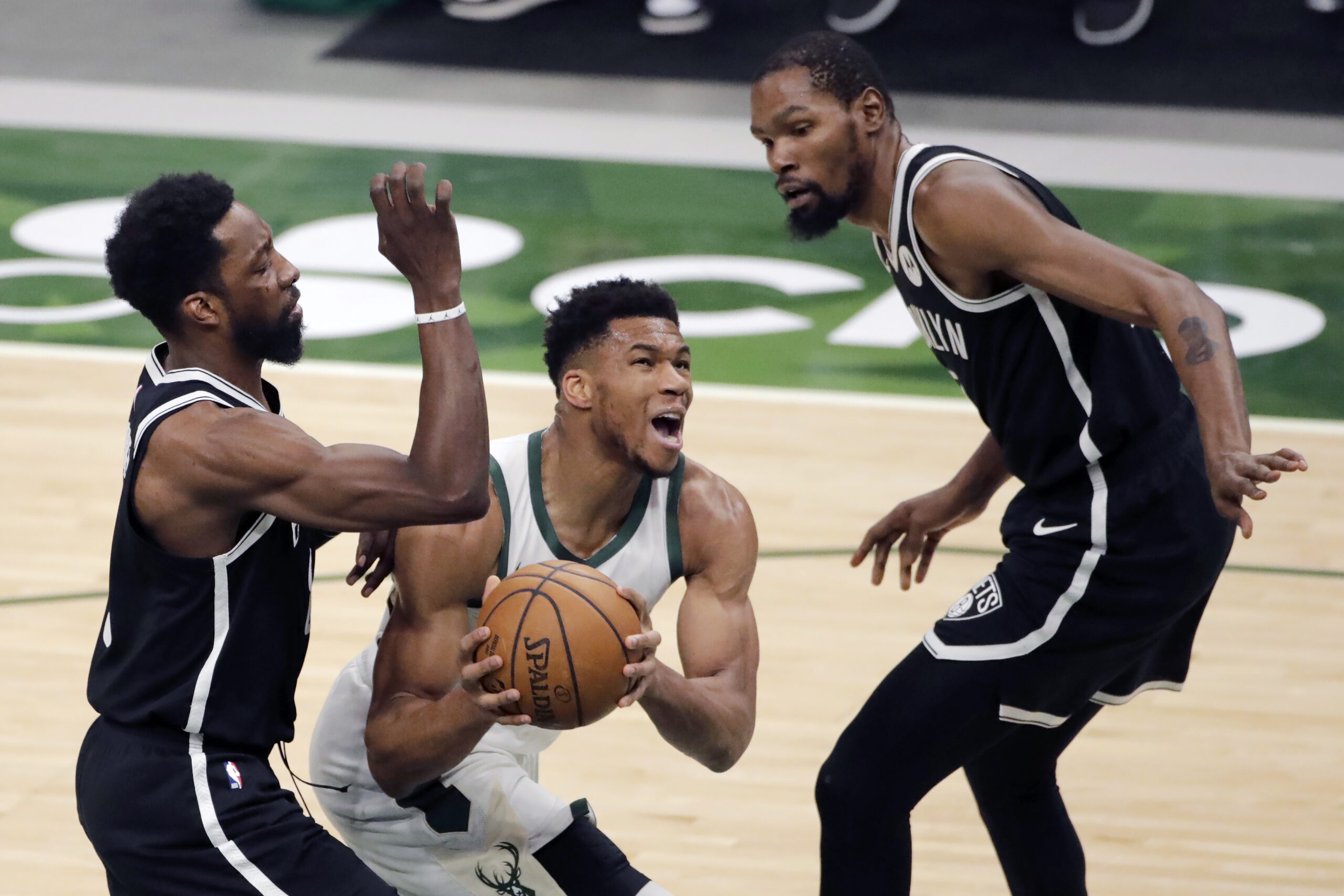 Giannis Antetokounmpo maneuvers between two Nets players