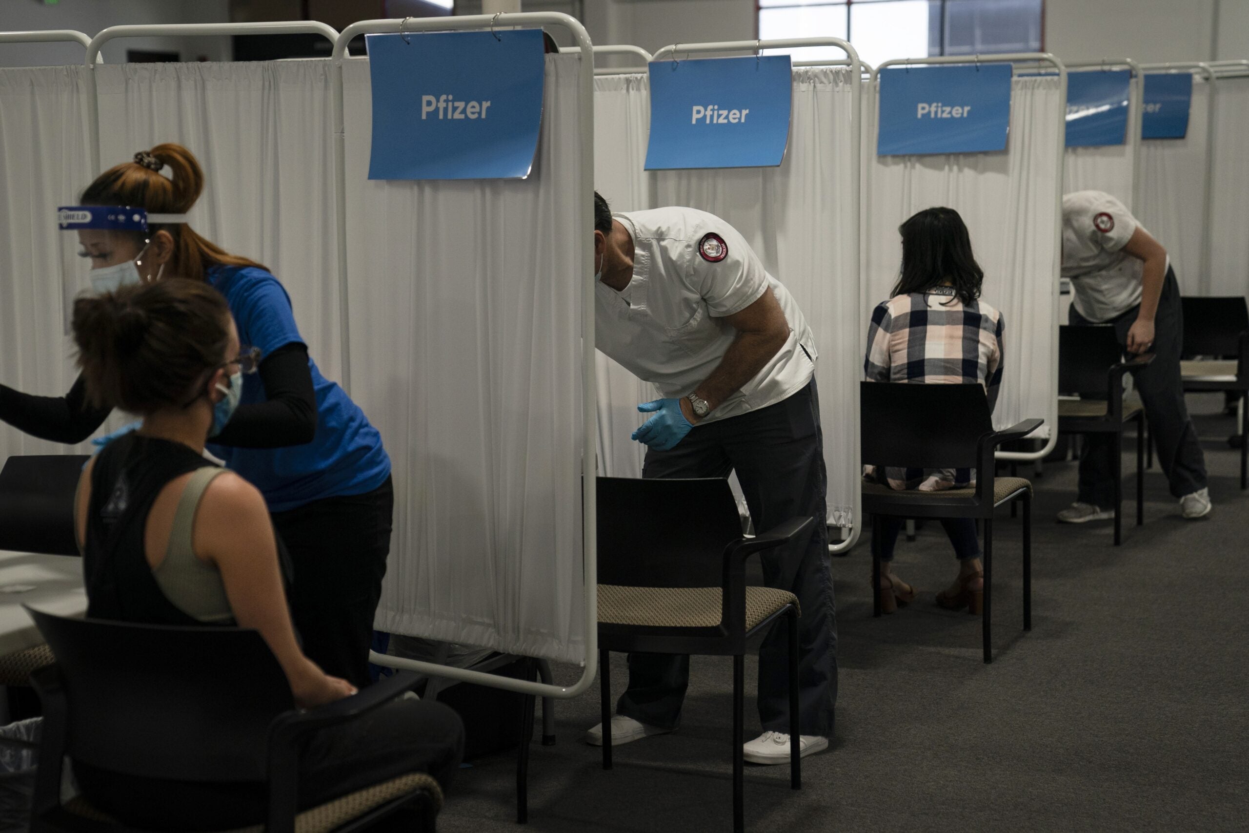 student nurse Dario Gomez disinfects a chair after administering the Pfizer COVID-19 vaccine