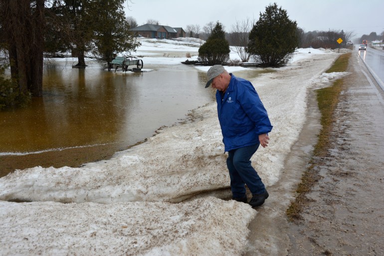 Arlin Karnopp takes water samples from his front yard during a rainstorm in the town of Montpelier