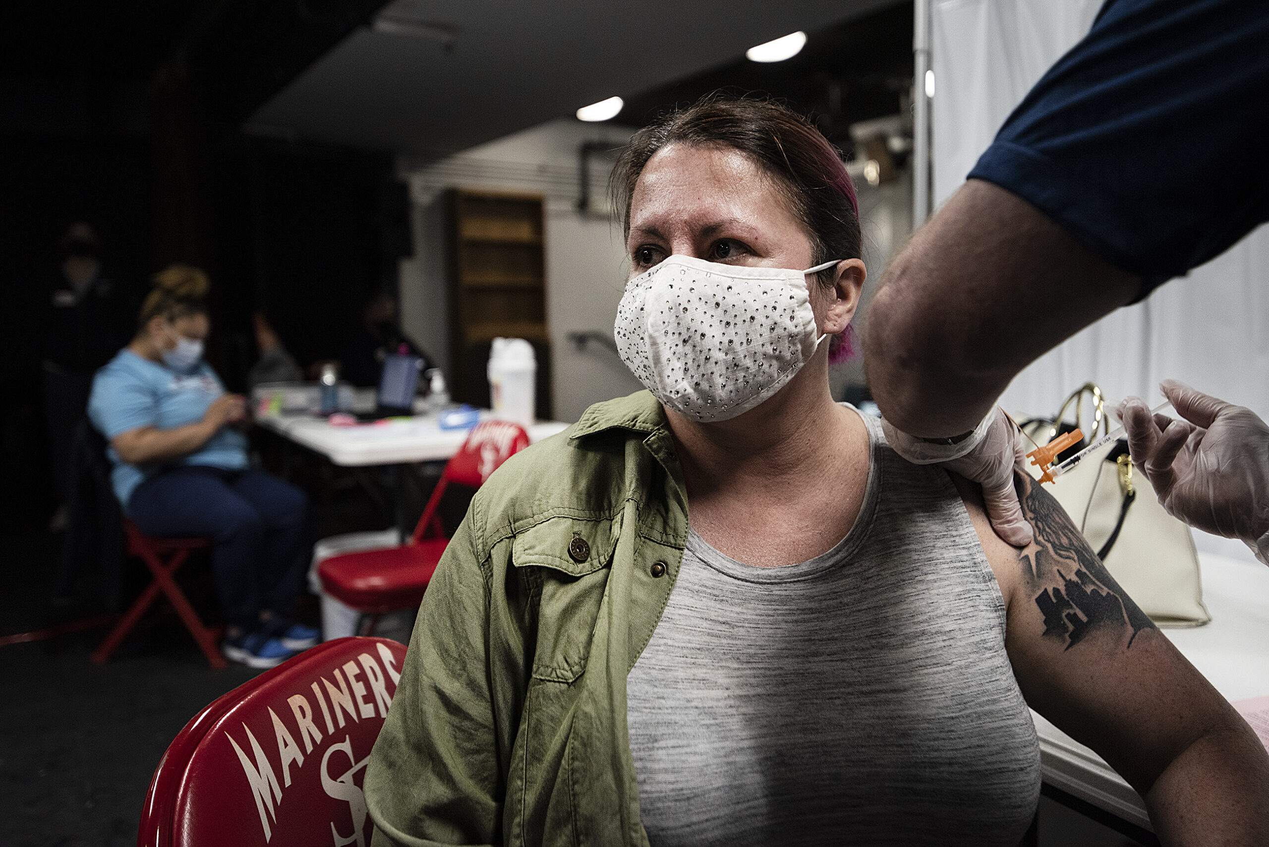 A woman wears a face mask as she receives a COVID-19 vaccine.