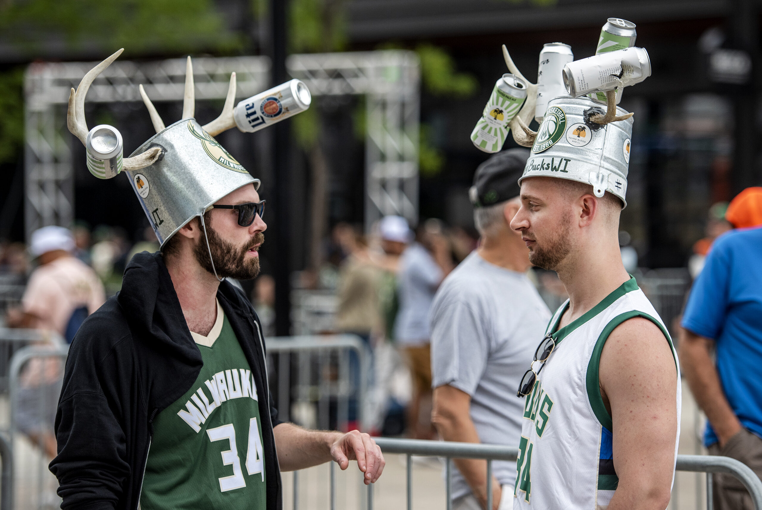 Two fans wear buckets on their heads with antlers and beer cans attached.