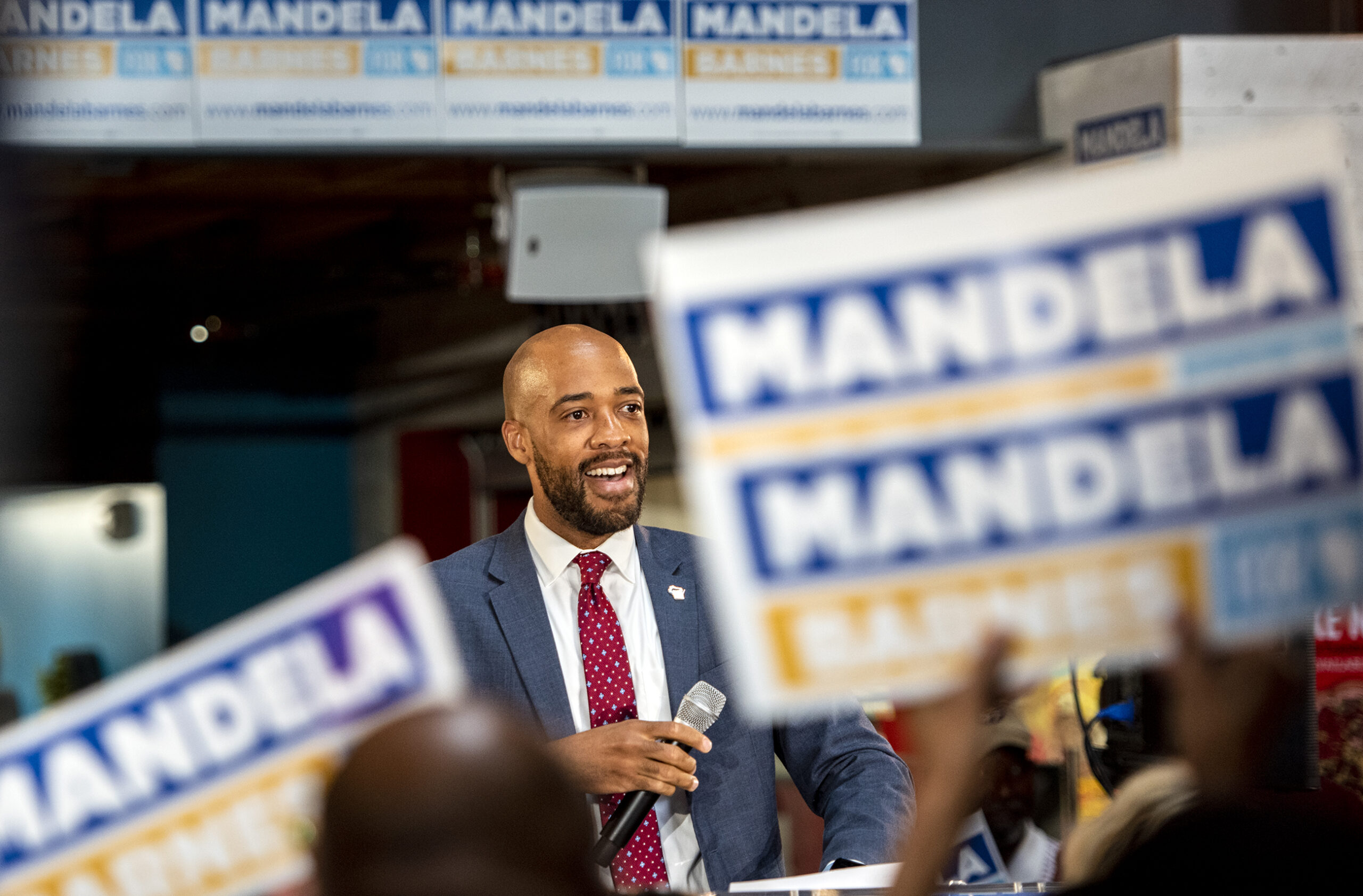 Signs that say "Mandela" on them are held up by supporters as Lt. Gov. Mandela Barnes takes the stage.