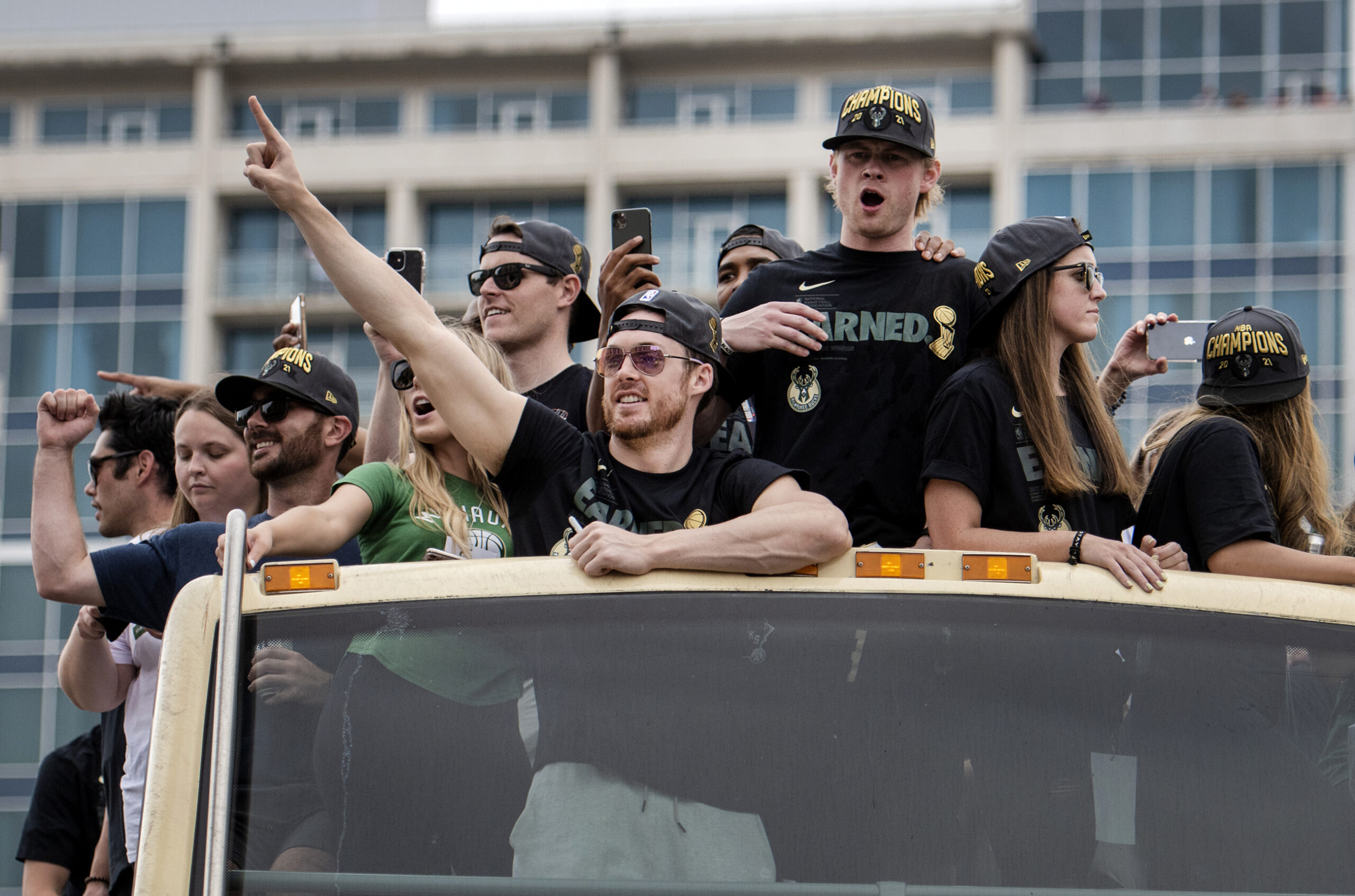 People look down at the crowd from on top of a bus.