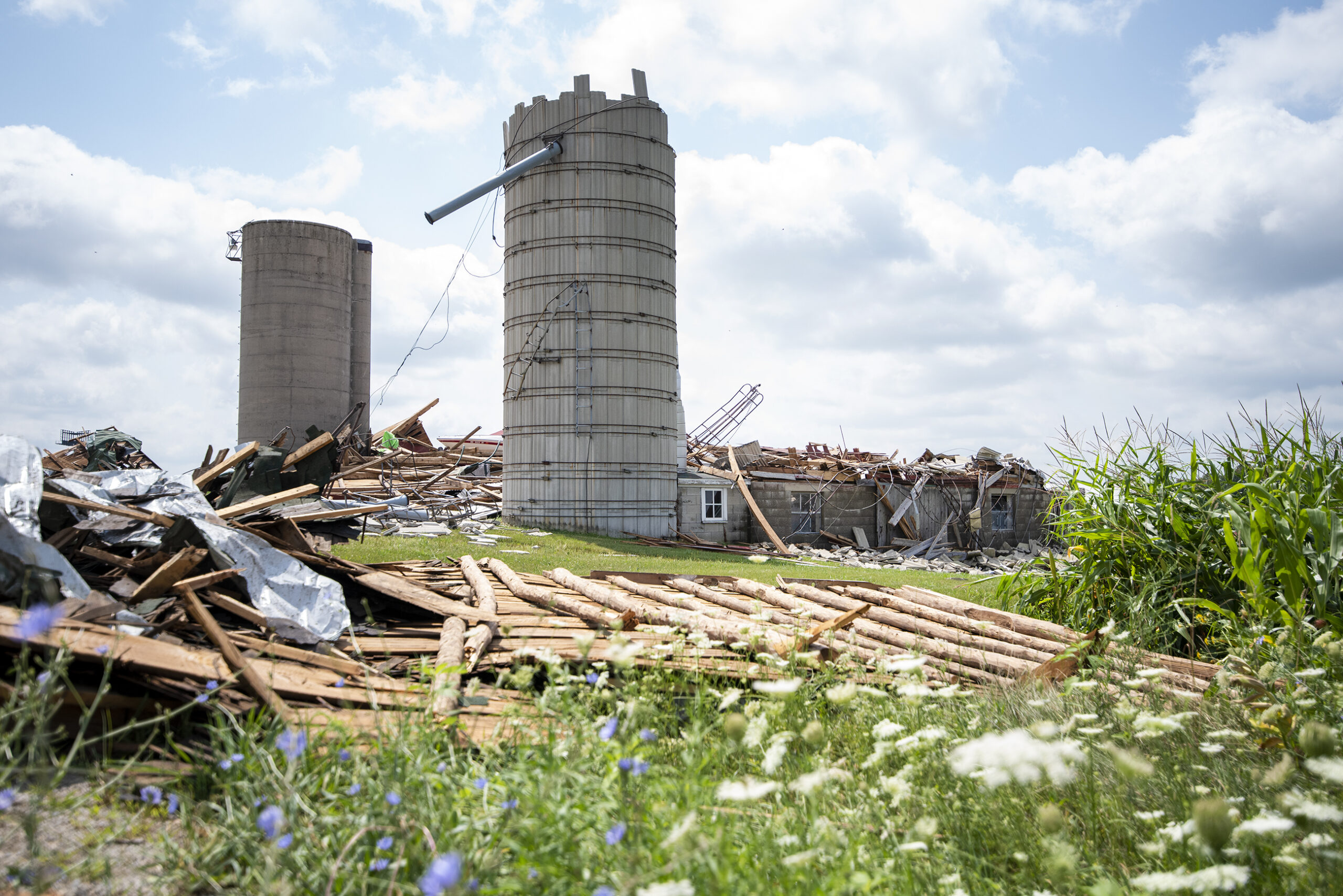 Two silos stand among a pile of wooden rubble.