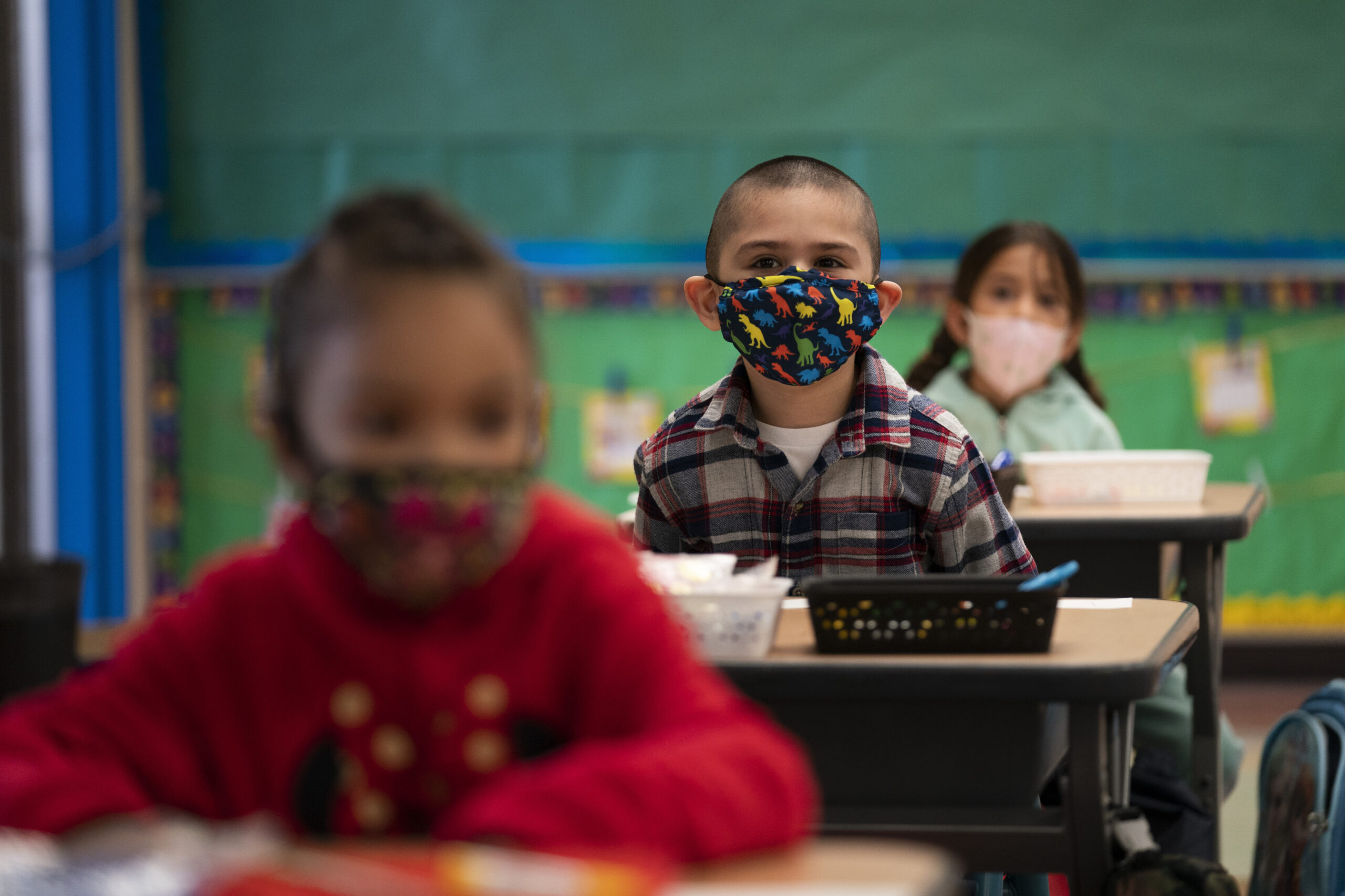 Kindergarten students wearing face masks sit in their classroom