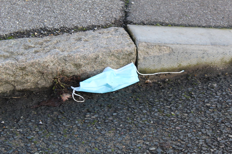 a surgical mask lays near a curb