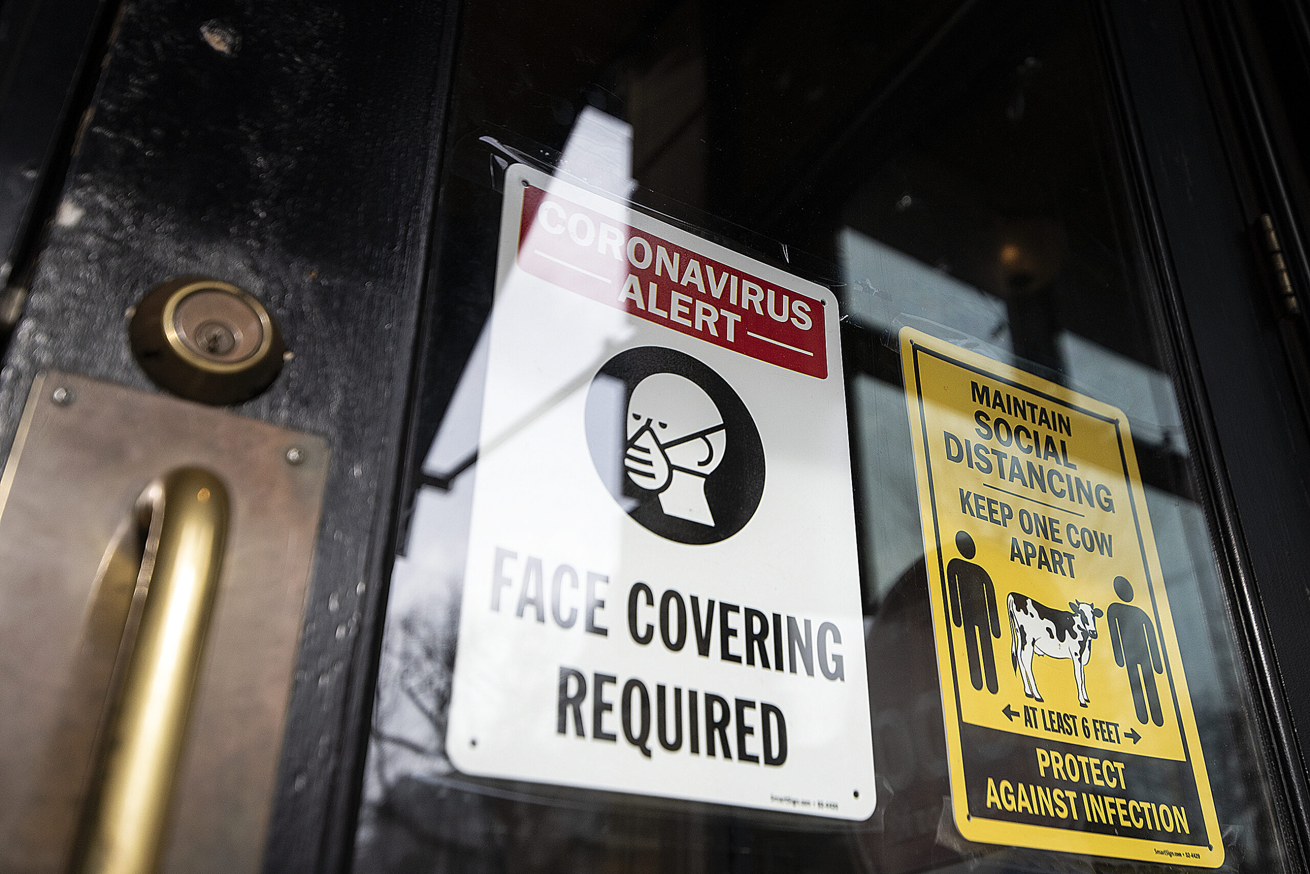 A sign on a clear glass door says "Face Covering Required."