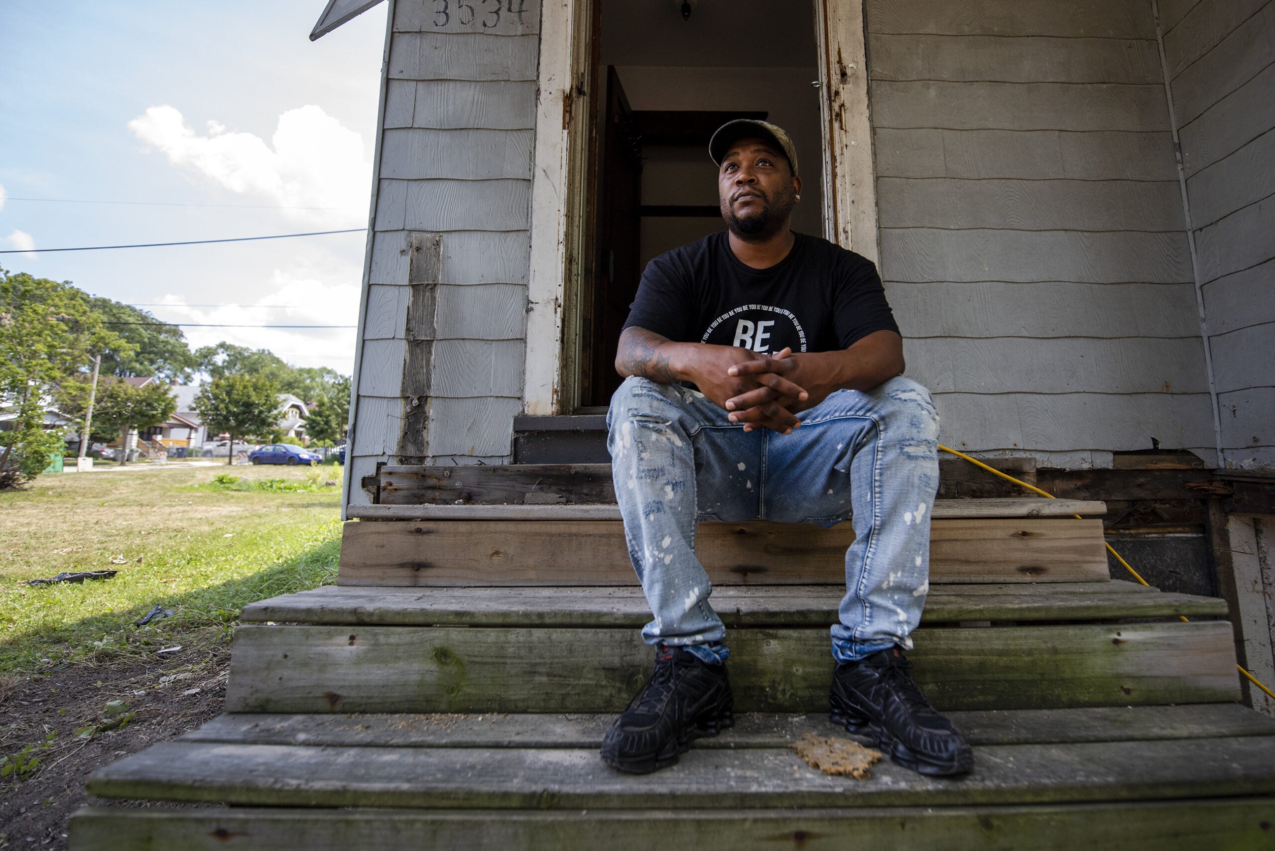 A man sits on the front steps of a home.