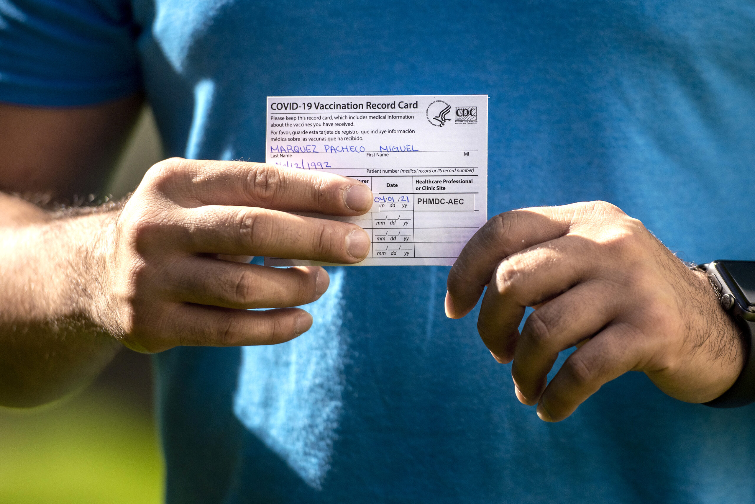 A white card with vaccine information is seen in someone's hands.