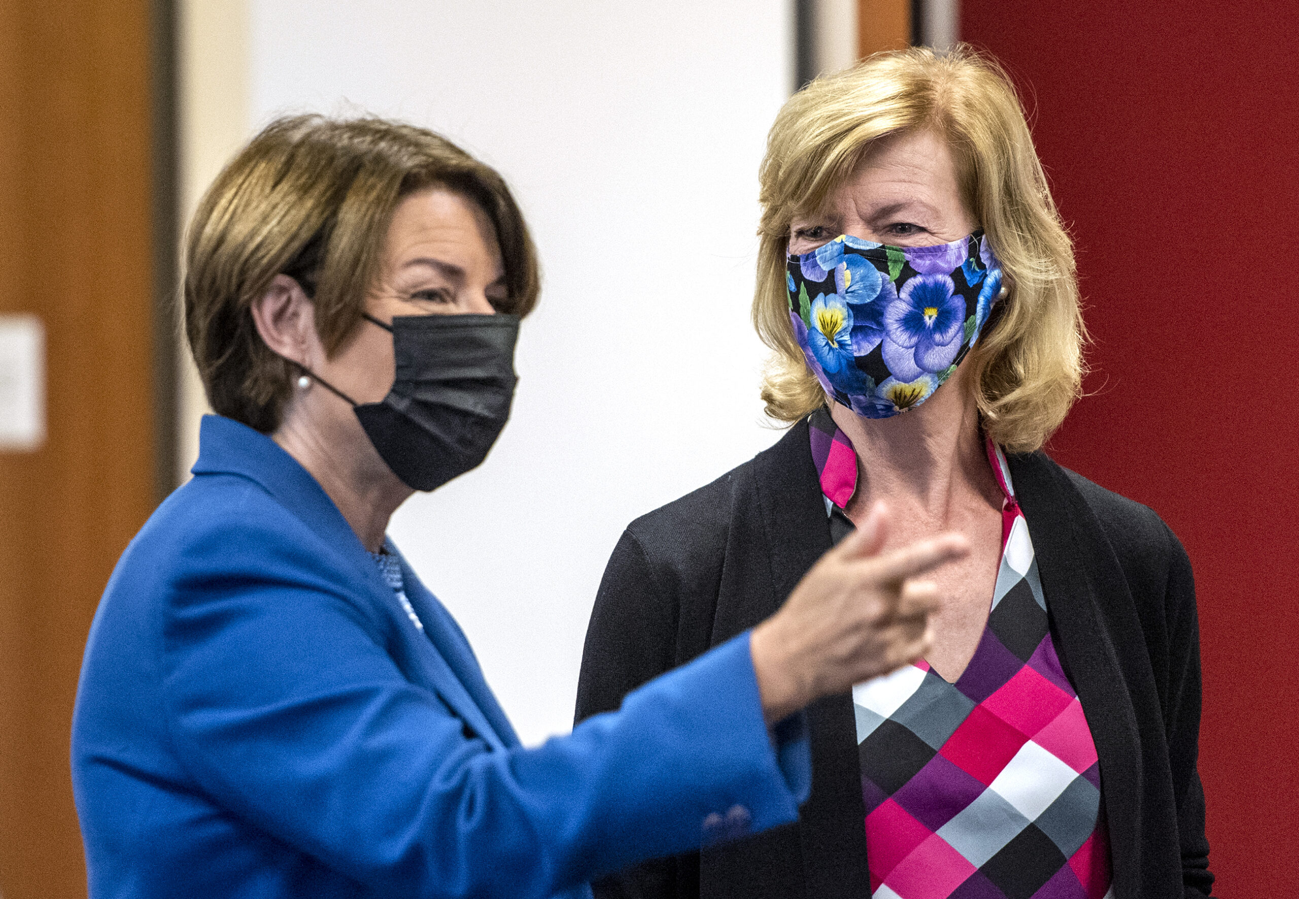 U.S. Senators Tammy Baldwin and Amy Klobuchar wear masks as they chat before the roundtable.