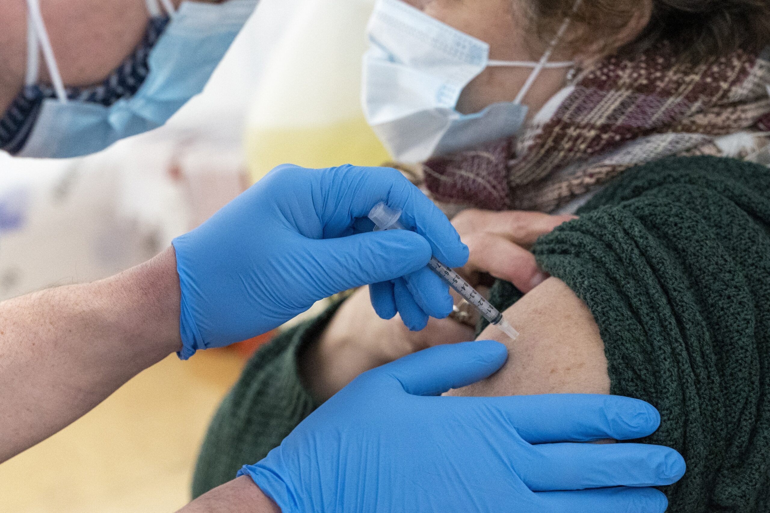 A nurse administers the first dose of the COVID-19 vaccine