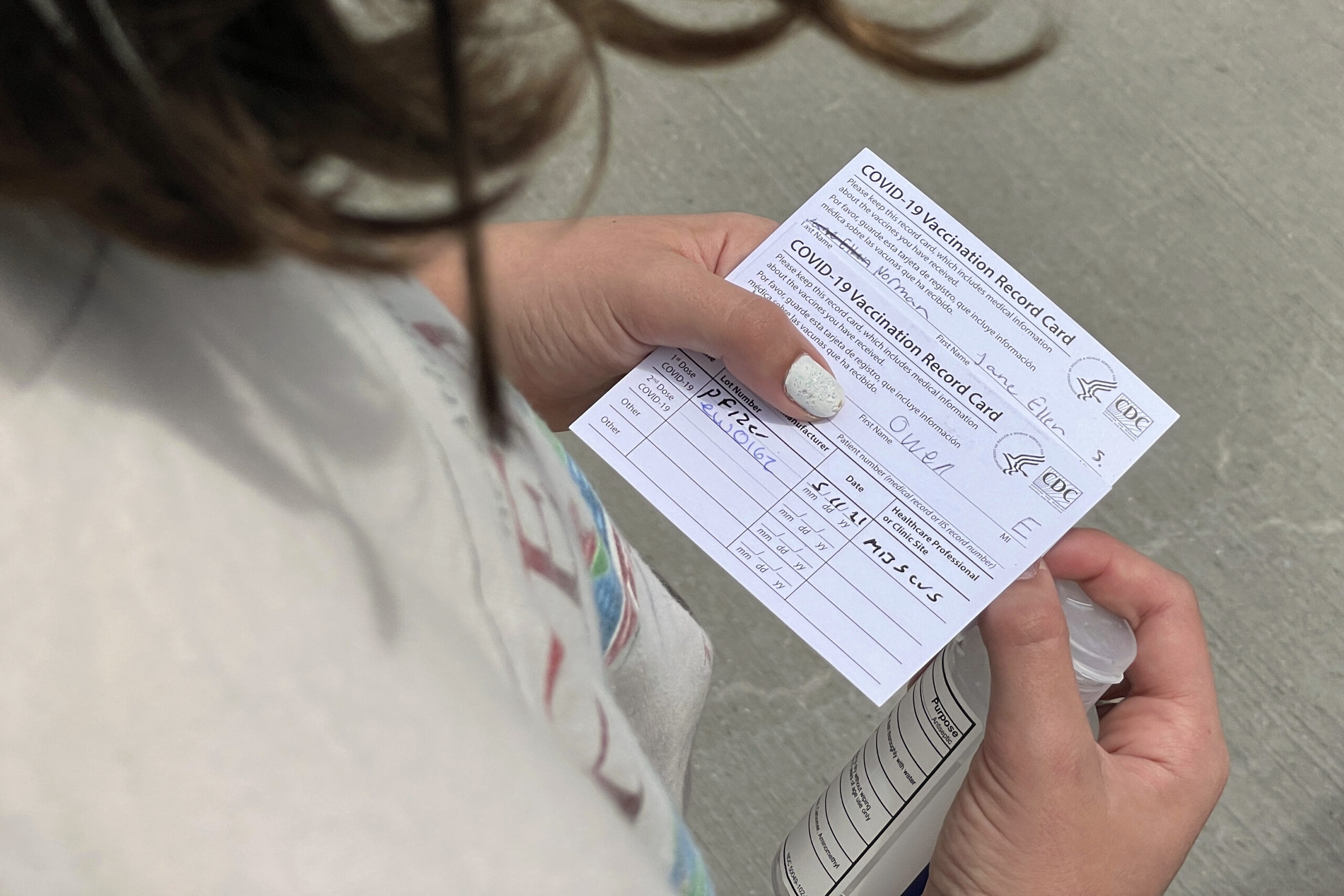 Jane Ellen Norman, 12, holds vaccination cards for her and her 14-year-old brother